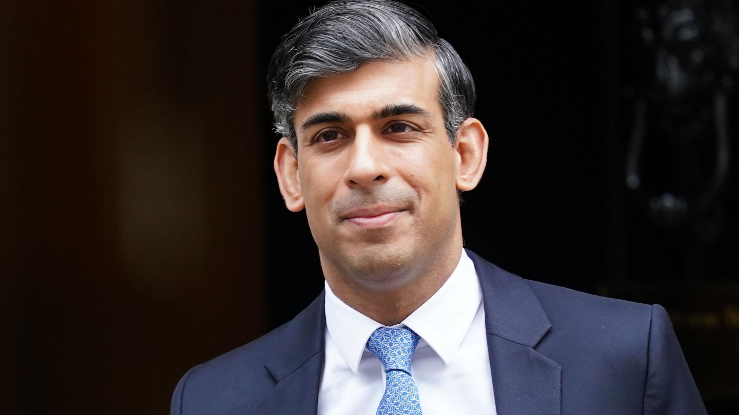 Rishi Sunak wearing a suit and blue tie is seen leaving 10 Downing Street during his final days as prime minister.