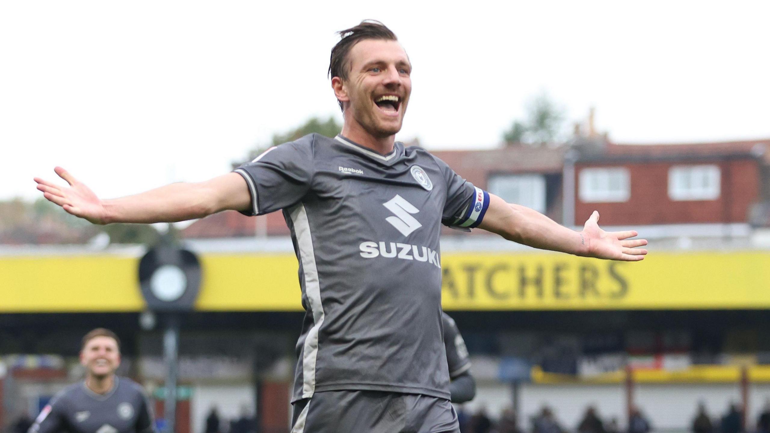 Alex Gilbey of Milton Keynes Dons celebrates a goal for his side by stretching out both arms