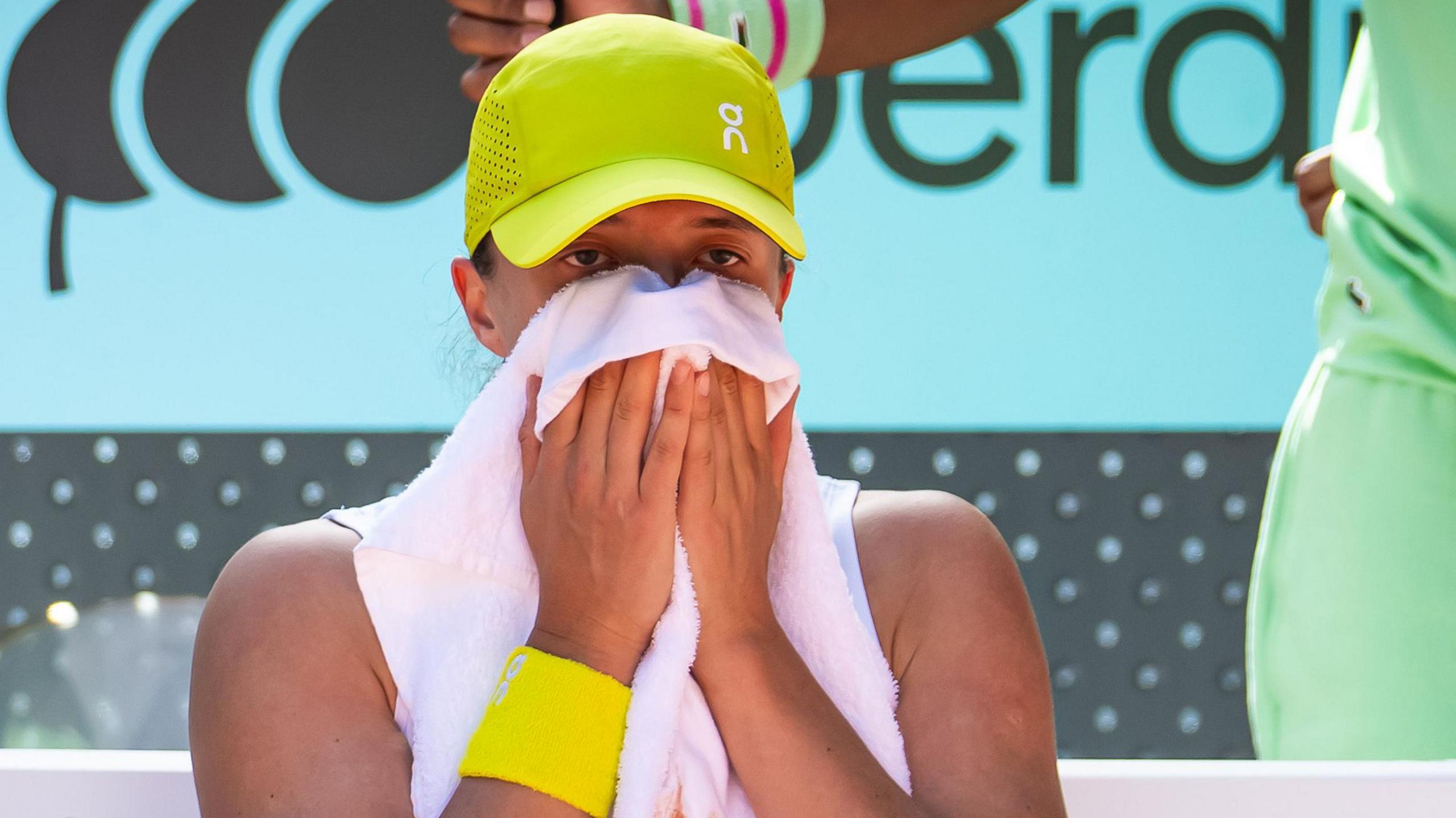 Iga Swiatek wipes her eyes with a towel during her defeat by Coco Gauff at the Madrid Open