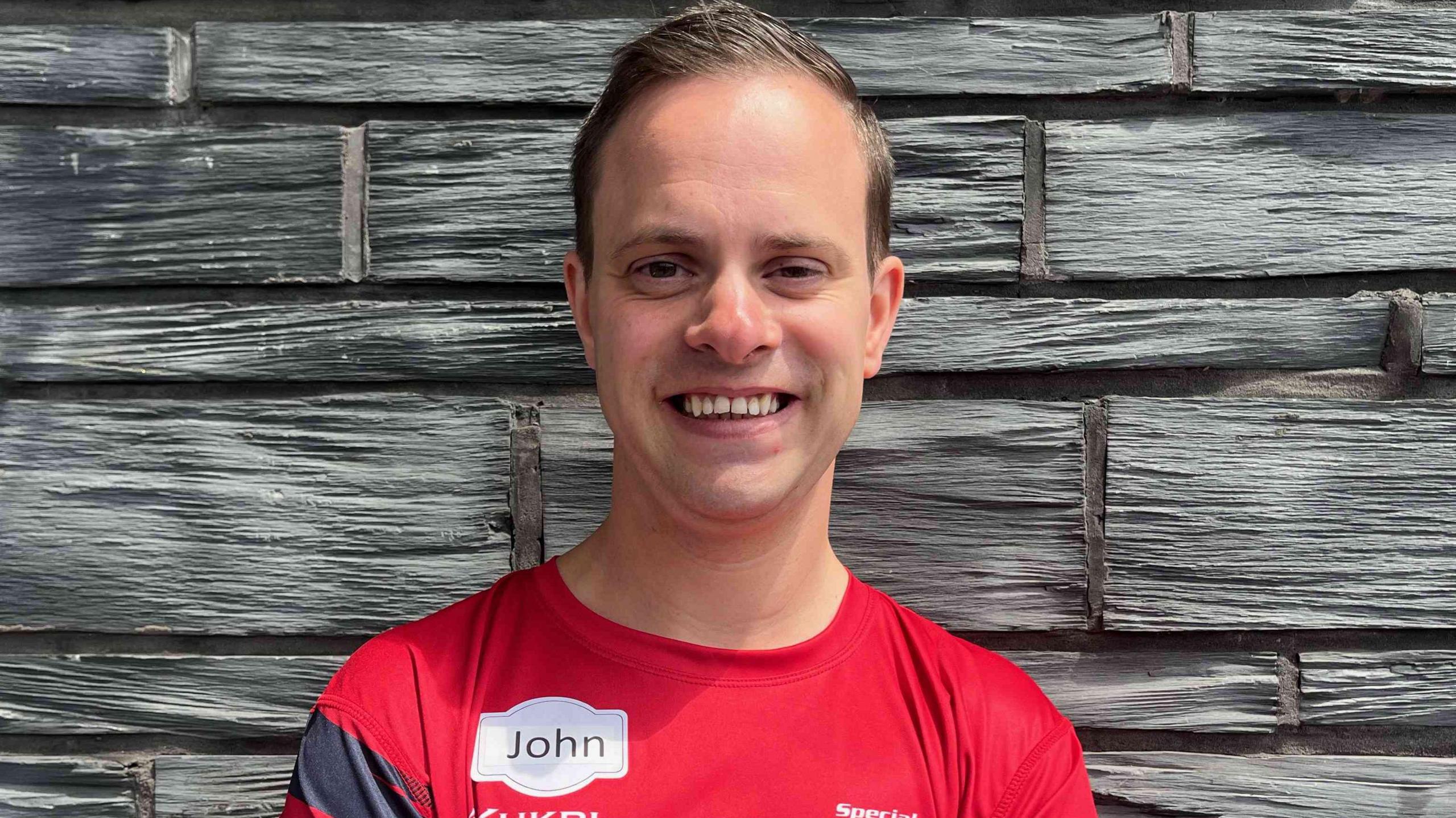 John stood outside the Senedd, smiling with his arms crossed