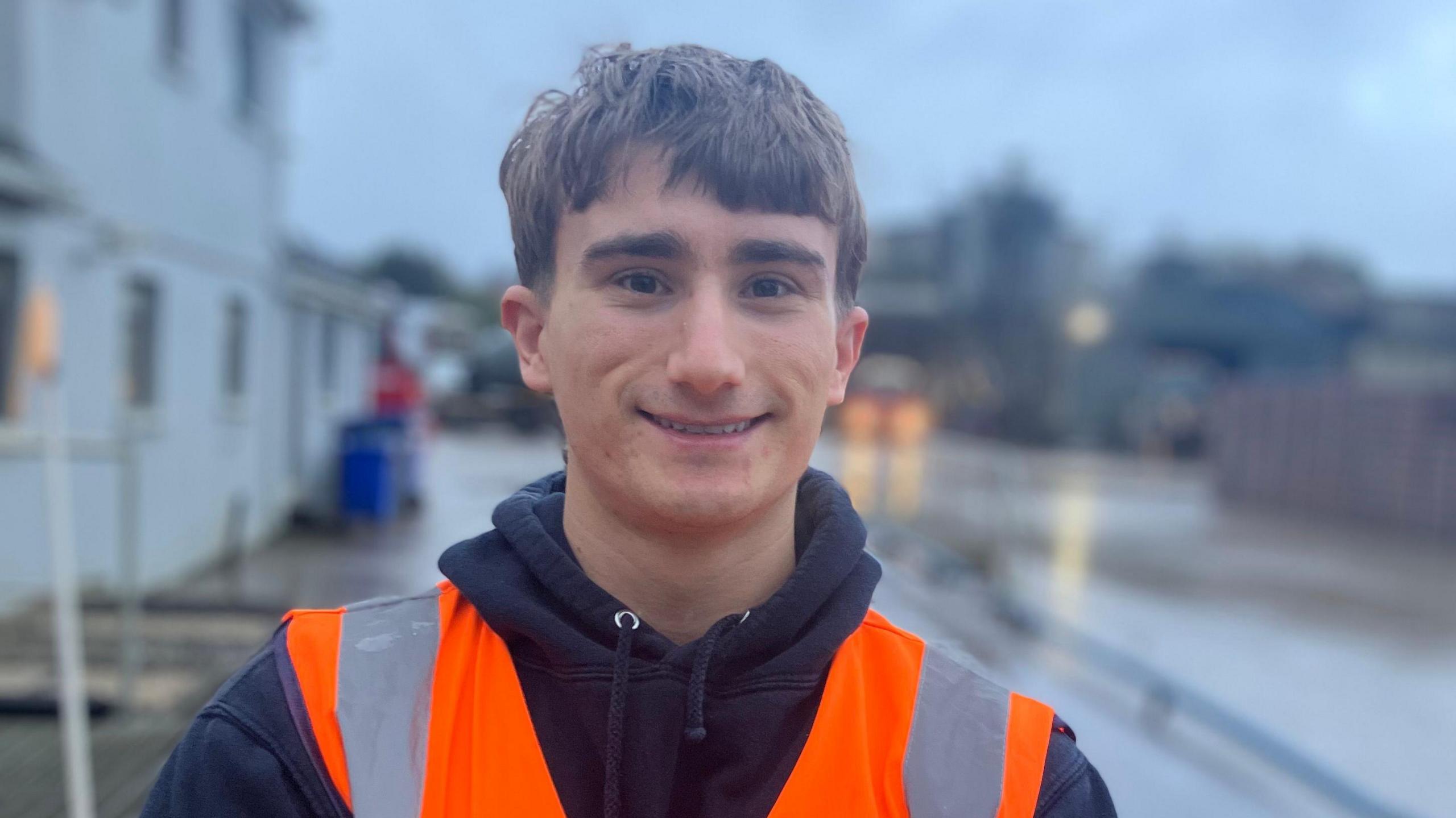 John Chambers Jr has brown hair and is wearing a high-vis vest in a quarry.
