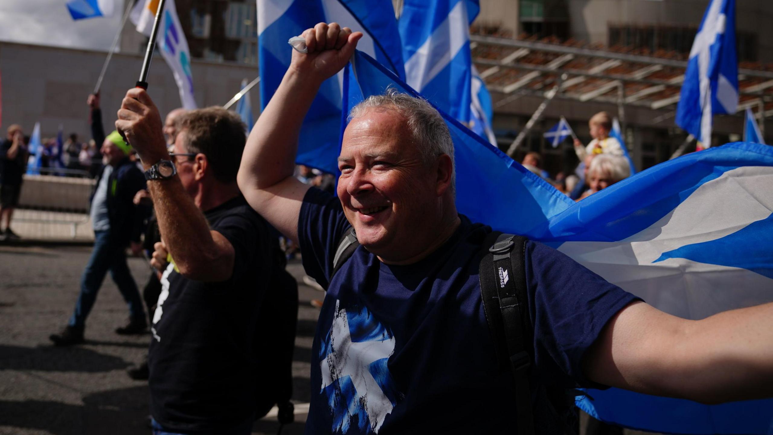 A smiling marcher with a saltire draped over his shoulders