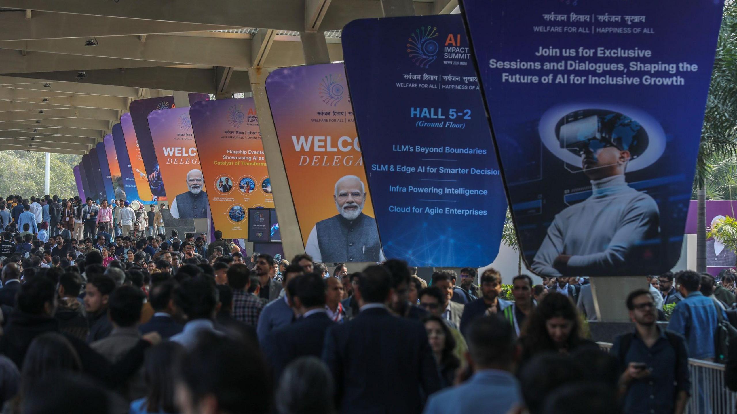 Visitors seen thronging the AI Impact Summit 2026 at Bharat Mandapam in New Delhi as posters of the event line the venue on 16 February 2026