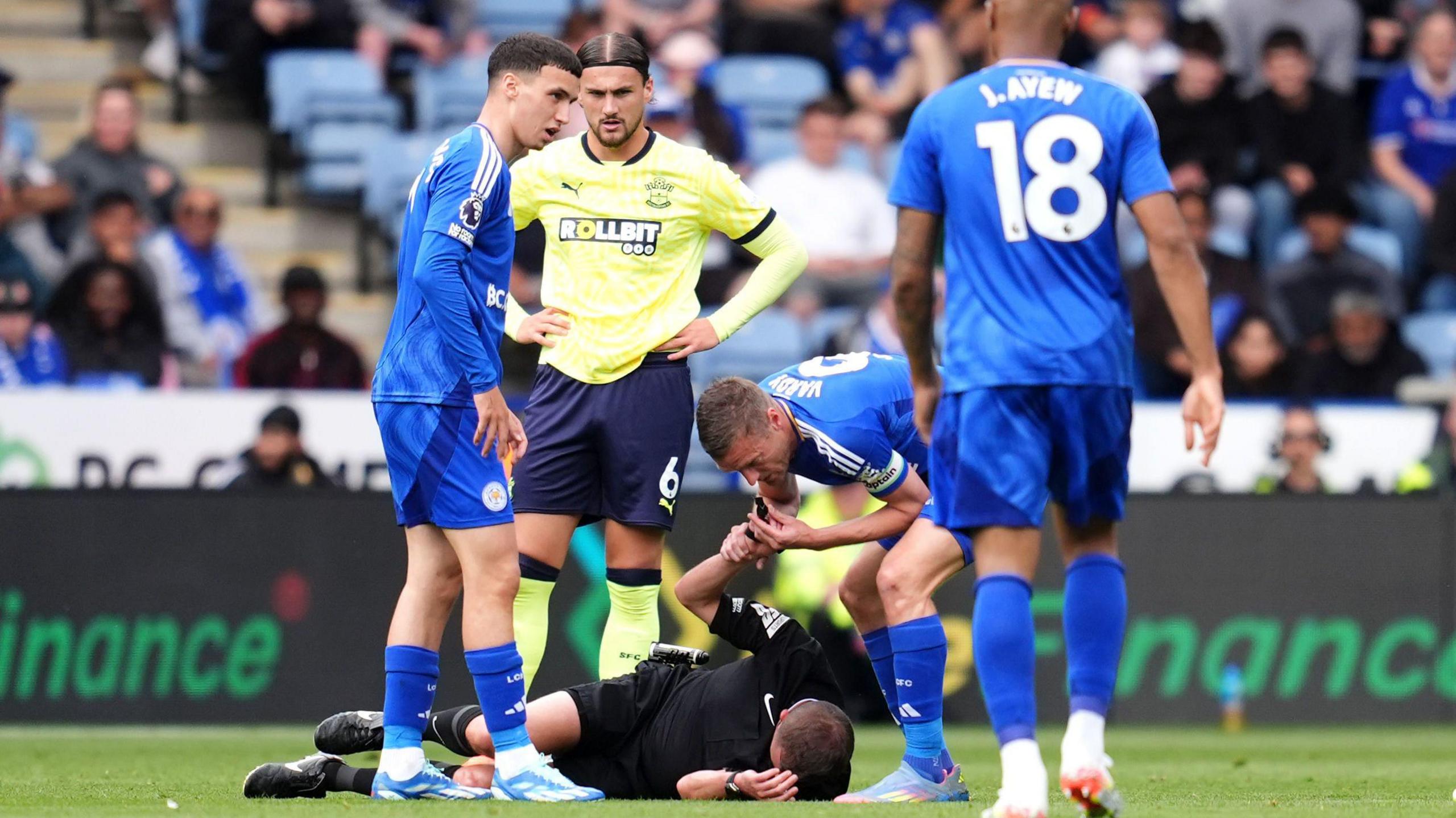 Referee David Webb appears injured after a collision with Leicester City's Jordan Ayew (right) as Jamie Vardy blows the referee whistle to stop play