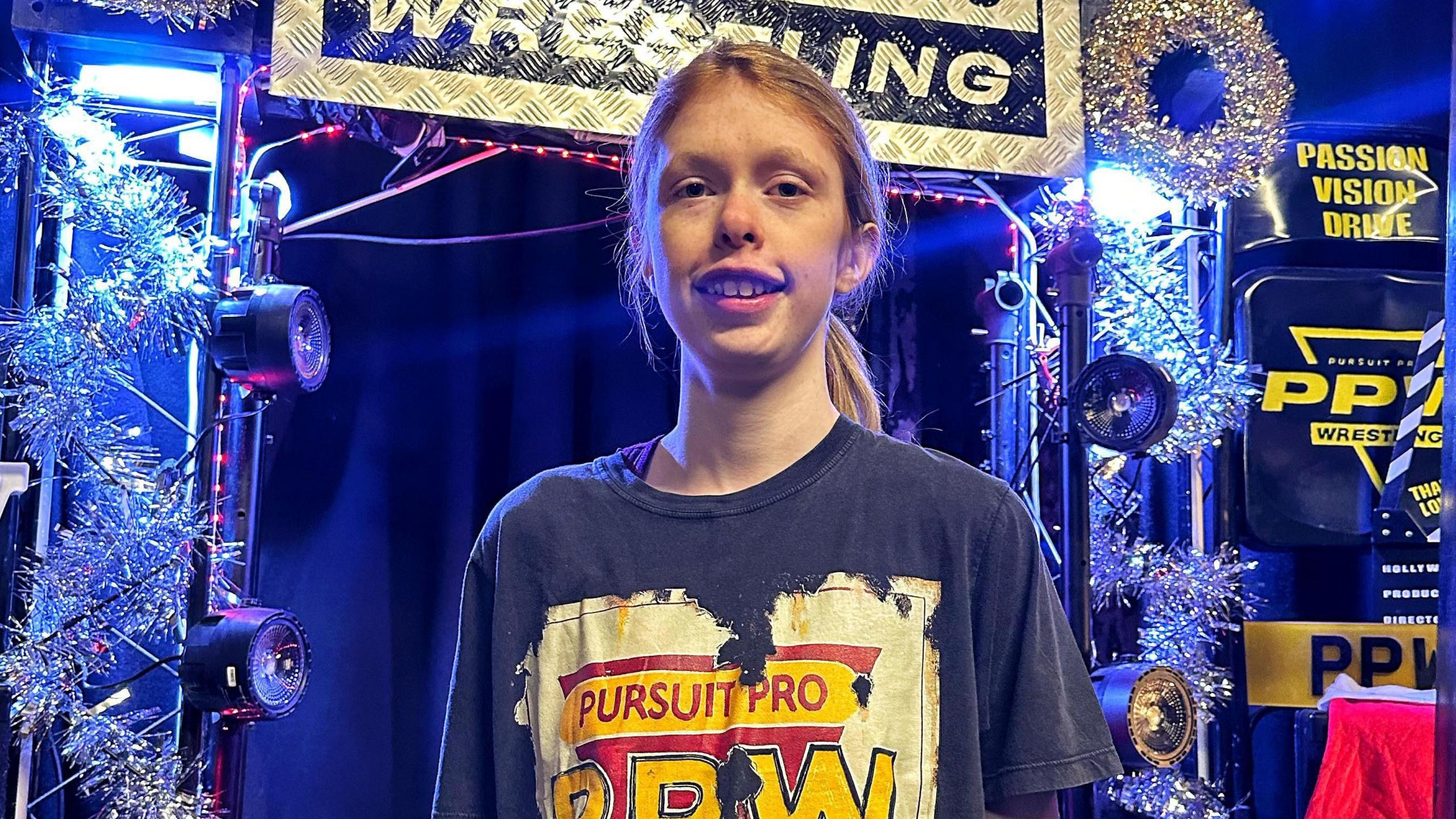 A young athlete poses in front of a stage with tinsel and light.