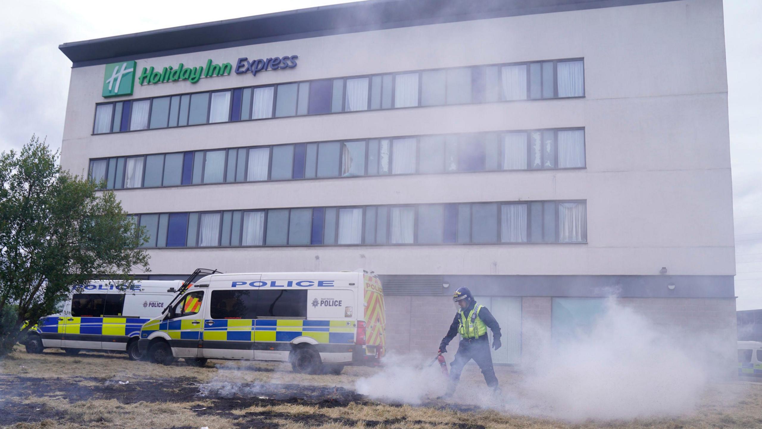 A police officer extinguishes a small fire during an anti-immigration demonstration outside the Holiday Inn Express in Rotherham, South Yorkshire.