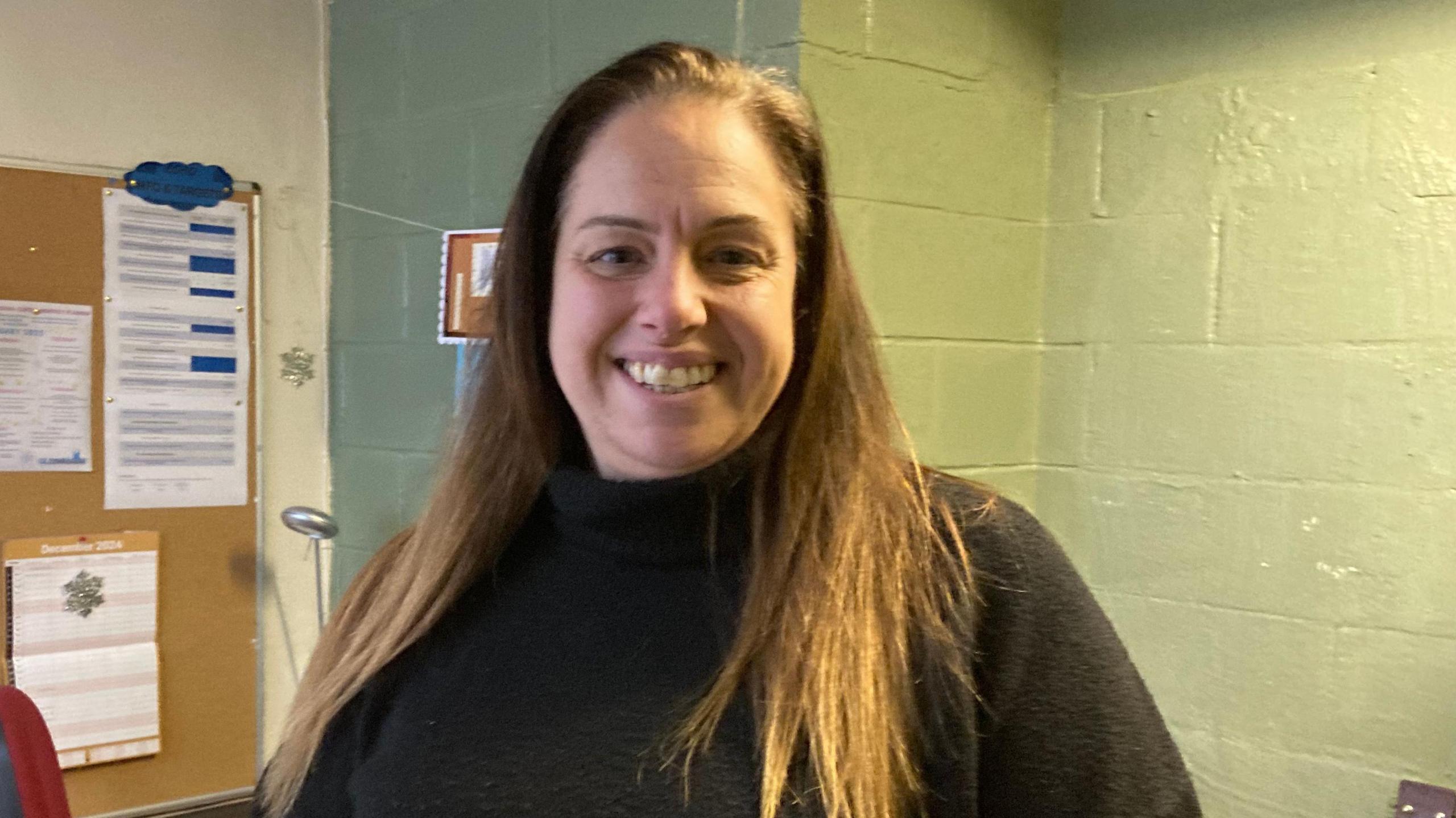 A photo of Amanda Bartlett who is the warm space head at the Phoenix Community Centre in Matson. She is smiling at the camera and has long fair hair and is wearing a dark-coloured jumper