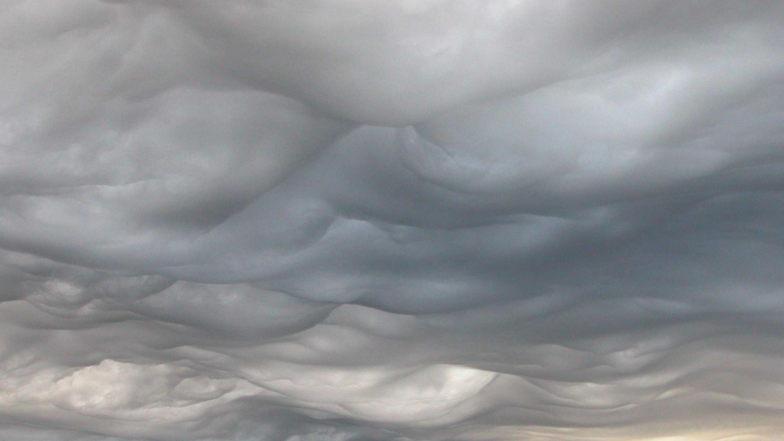 Image of a wide sky with heavy, undulating cloud over a landscape