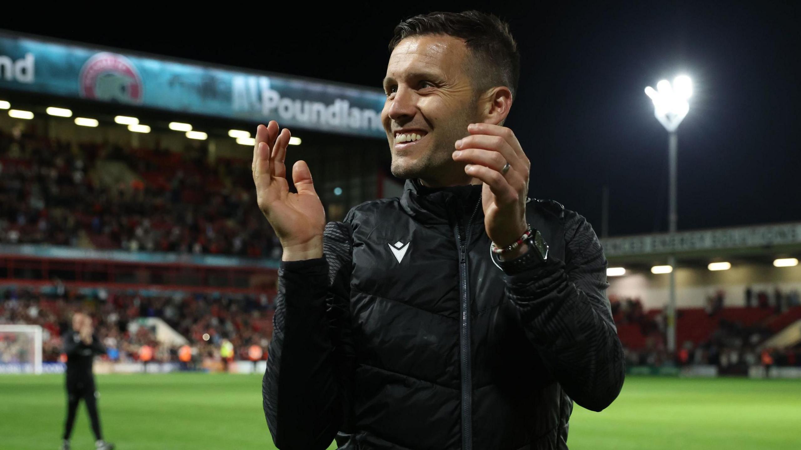 Walsall boss Mat Sadler smiles and claps the fans after a night game