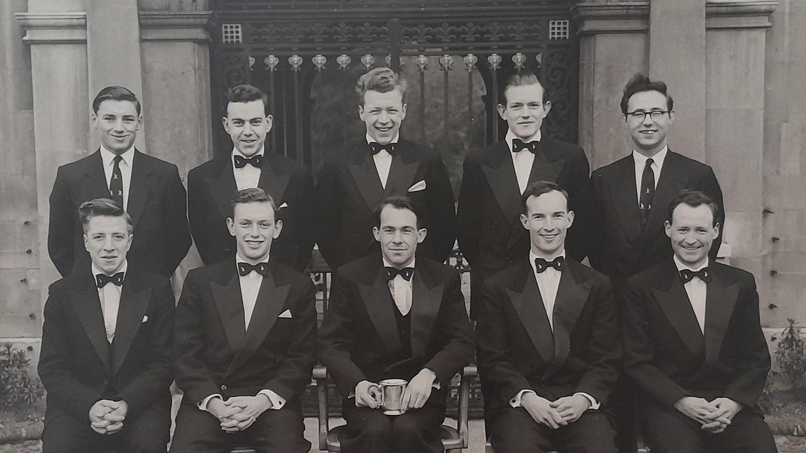 A black and white photo of the Cambridge University Tiddlywinks Club in 1958. There are two rows of men, smartly dressed in suits with bow ties. Bill Steen is in the front row, second from right. Lawford Howells is in the front row on the far right and Peter Downes is on the front row, second from the left.