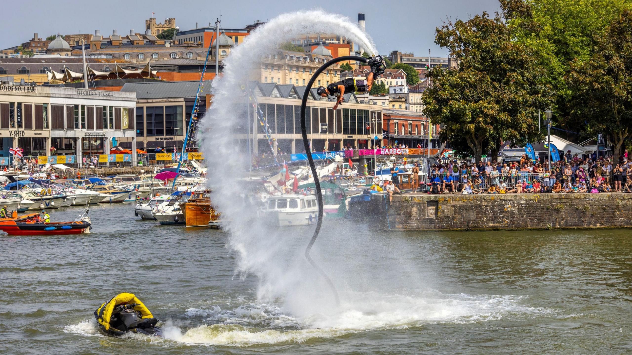 A man several feet in the air on Bristol harbour, using a flyboard