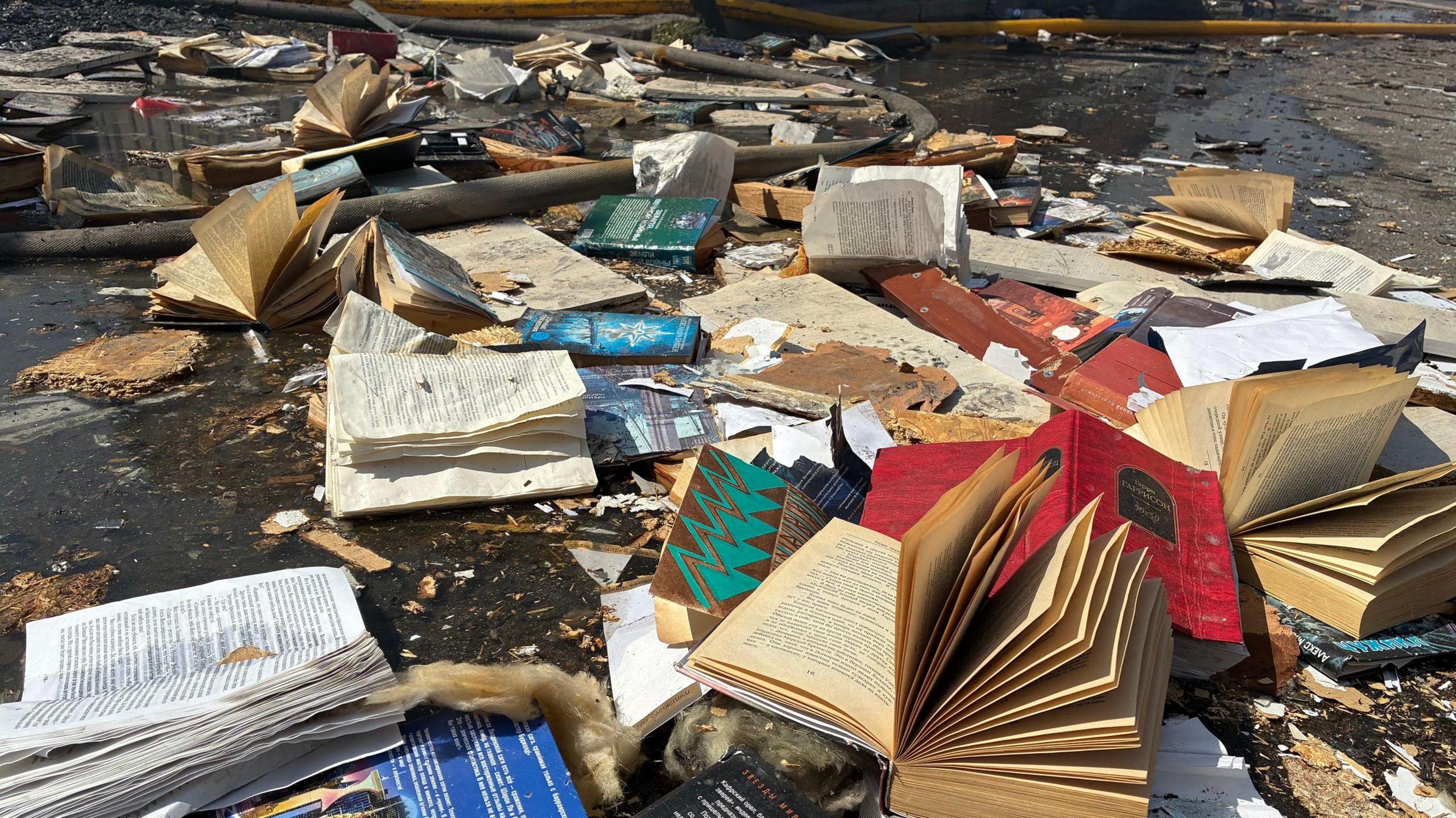 Books strewn across the ground all damaged and burnt