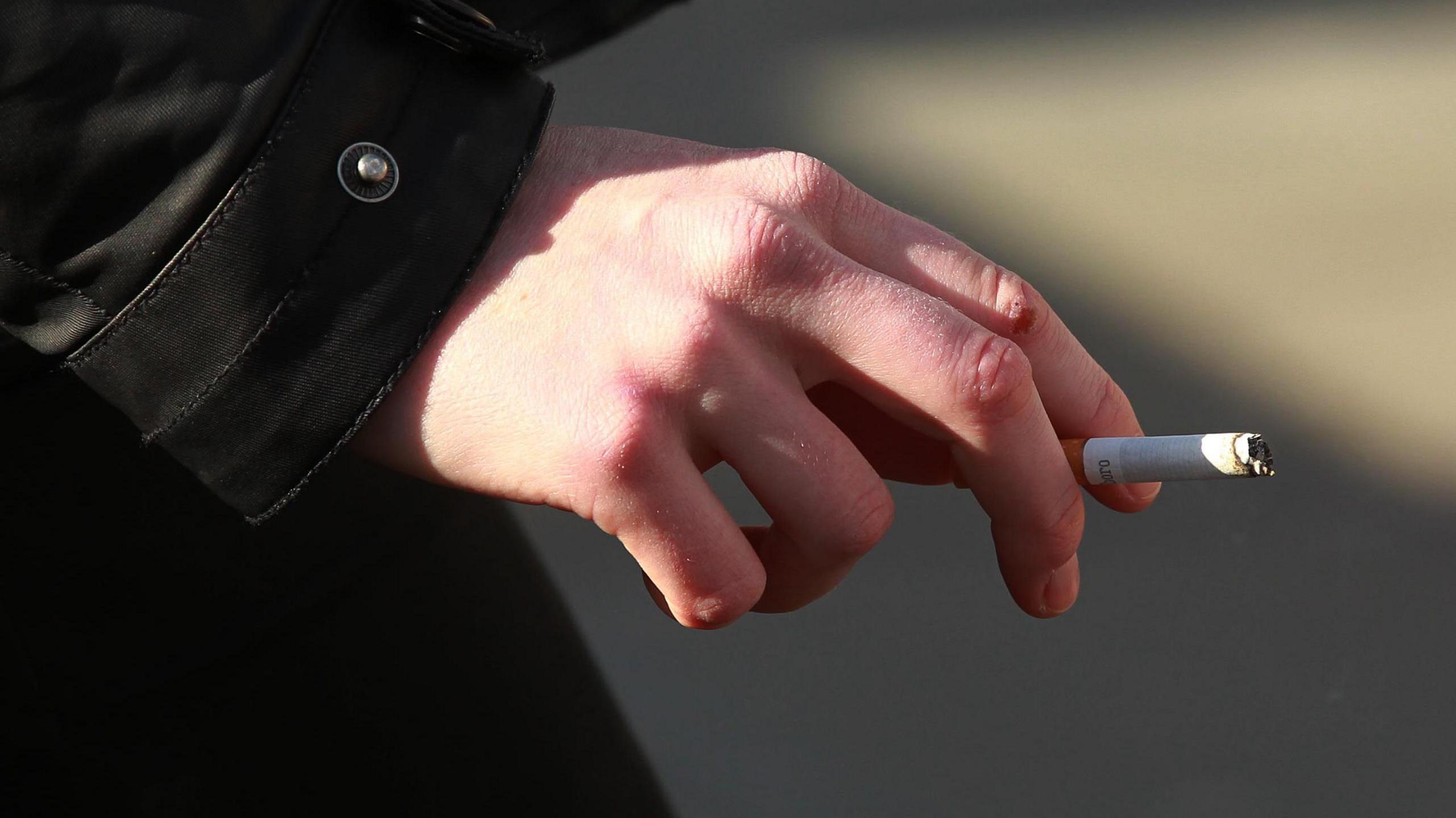 Person holds a cigarette in their fingers