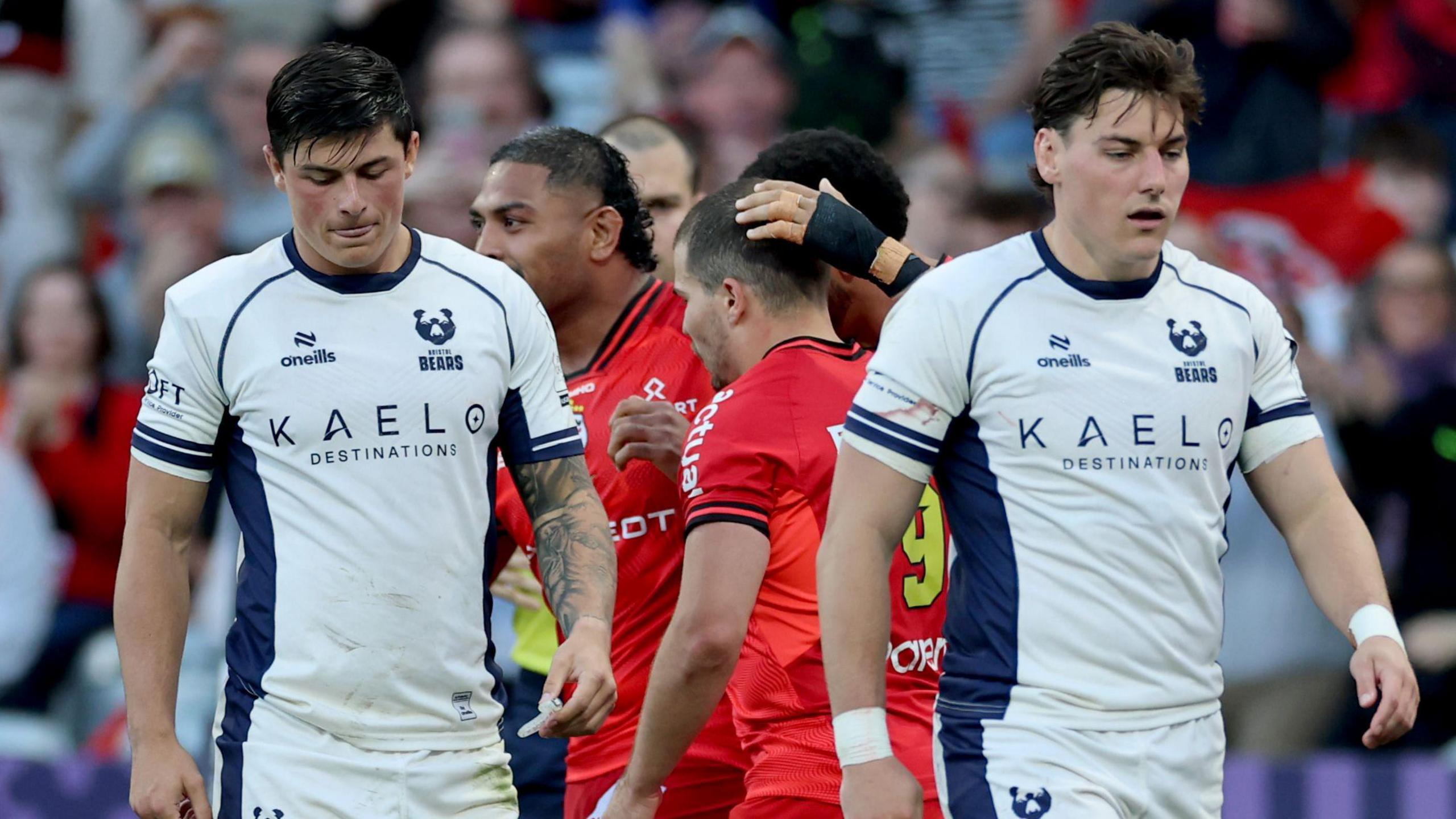 Louis Rees-Zammit (left) walks on the pitch with his head tilted down with Tom Jordan (right) walking next to him after a Toulouse try