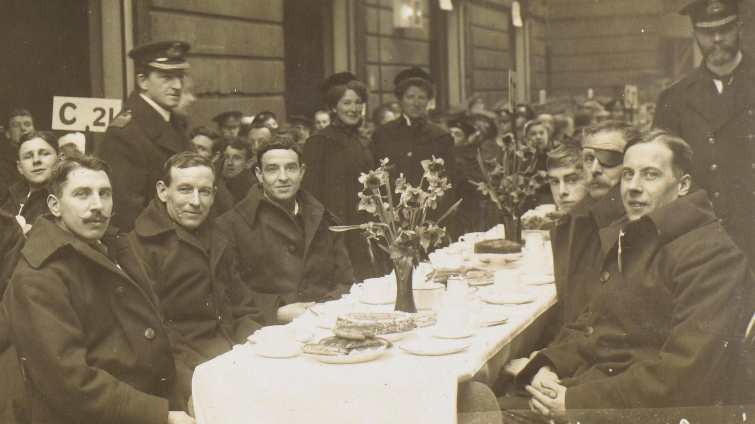 A black and white image of a group of World War One soldiers standing and sitting at tables in the Mews. 