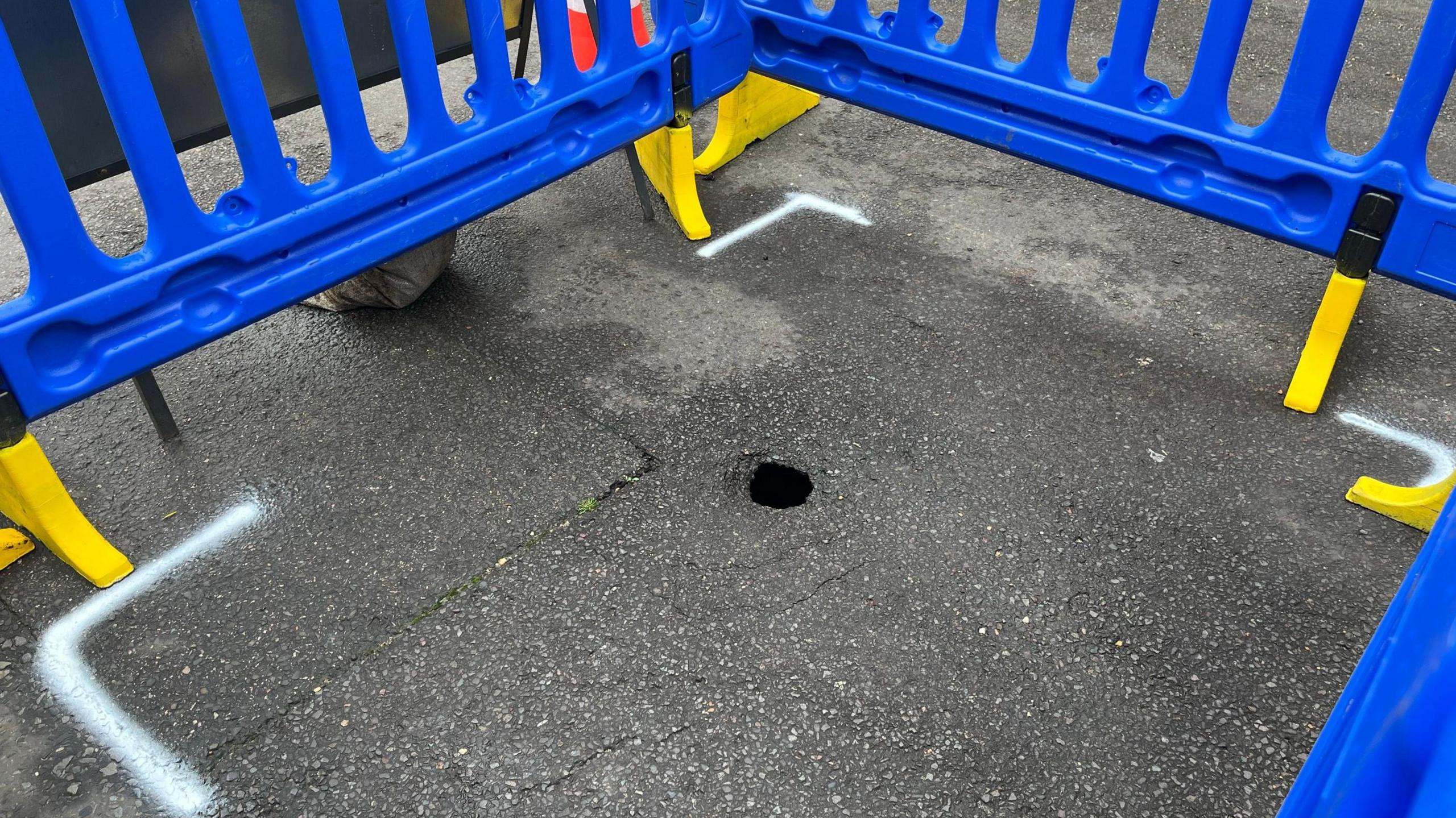 The sinkhole surrounded by plastic fencing. It is the size of a tennis ball on the surface but about six foot wide underneath