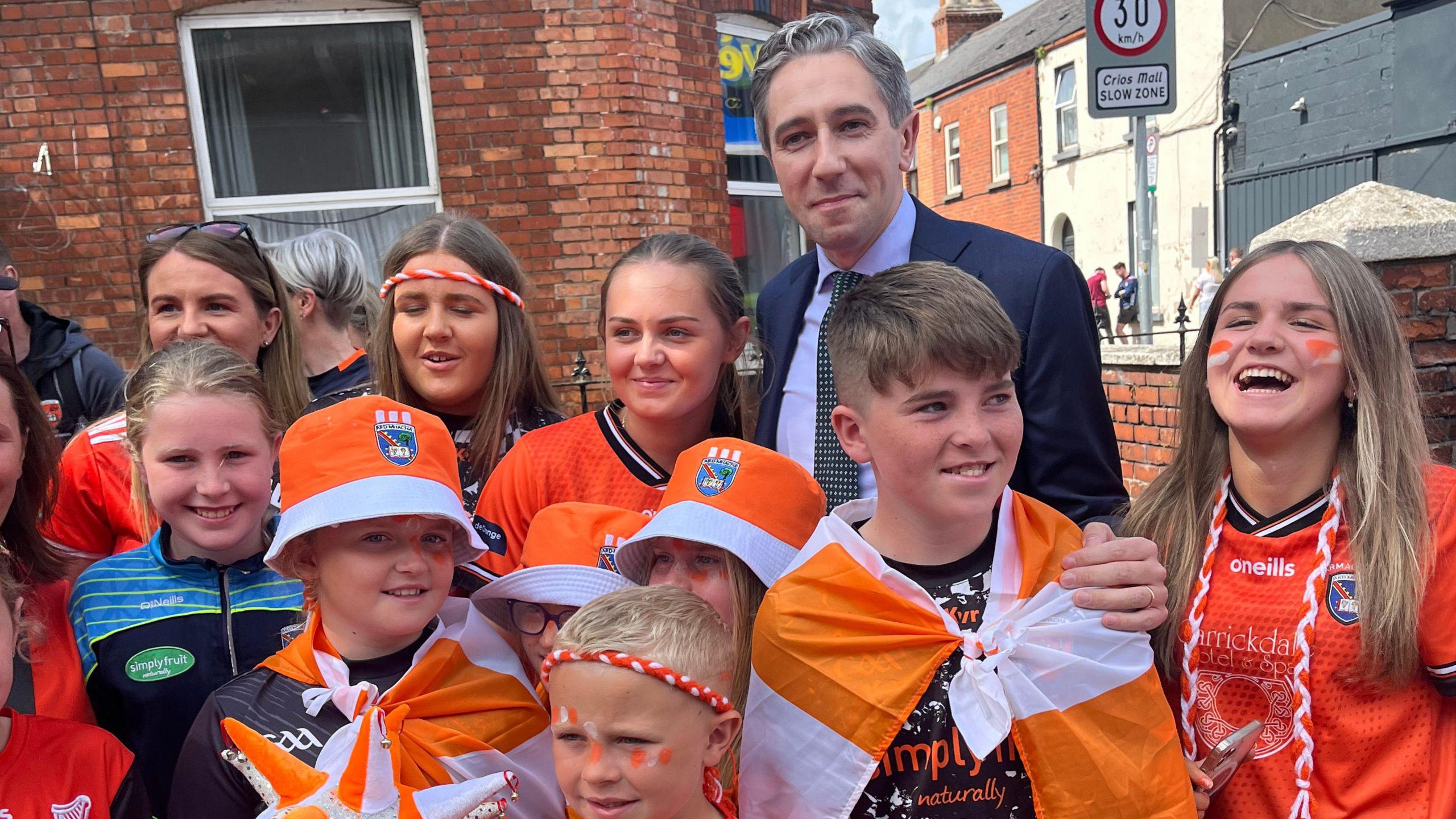 Simon Harris standing with a group of kids who are all wearing orange