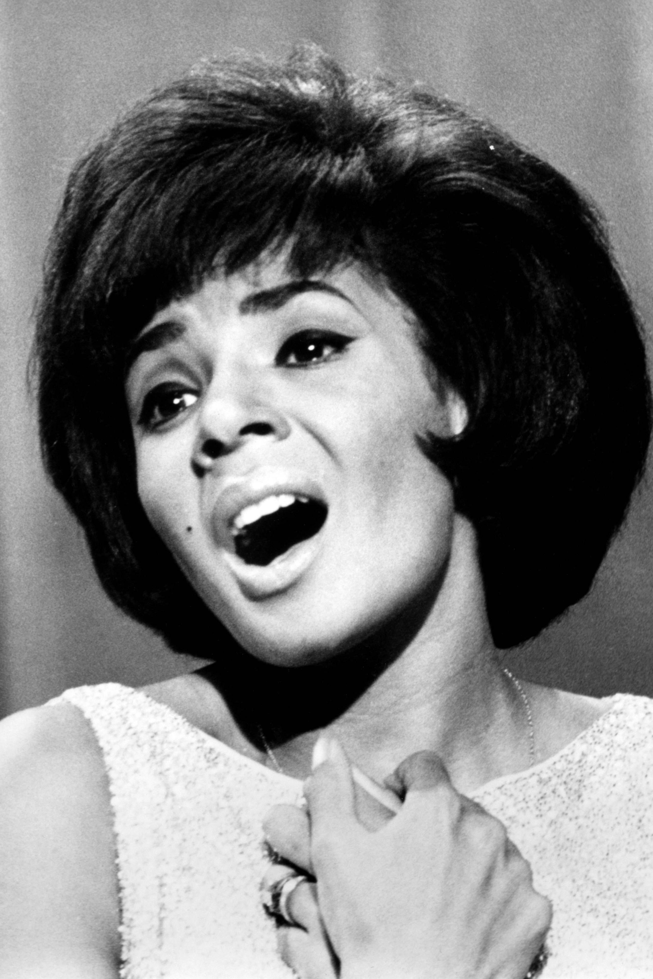 Shirley Bassey singing wearing a white dress