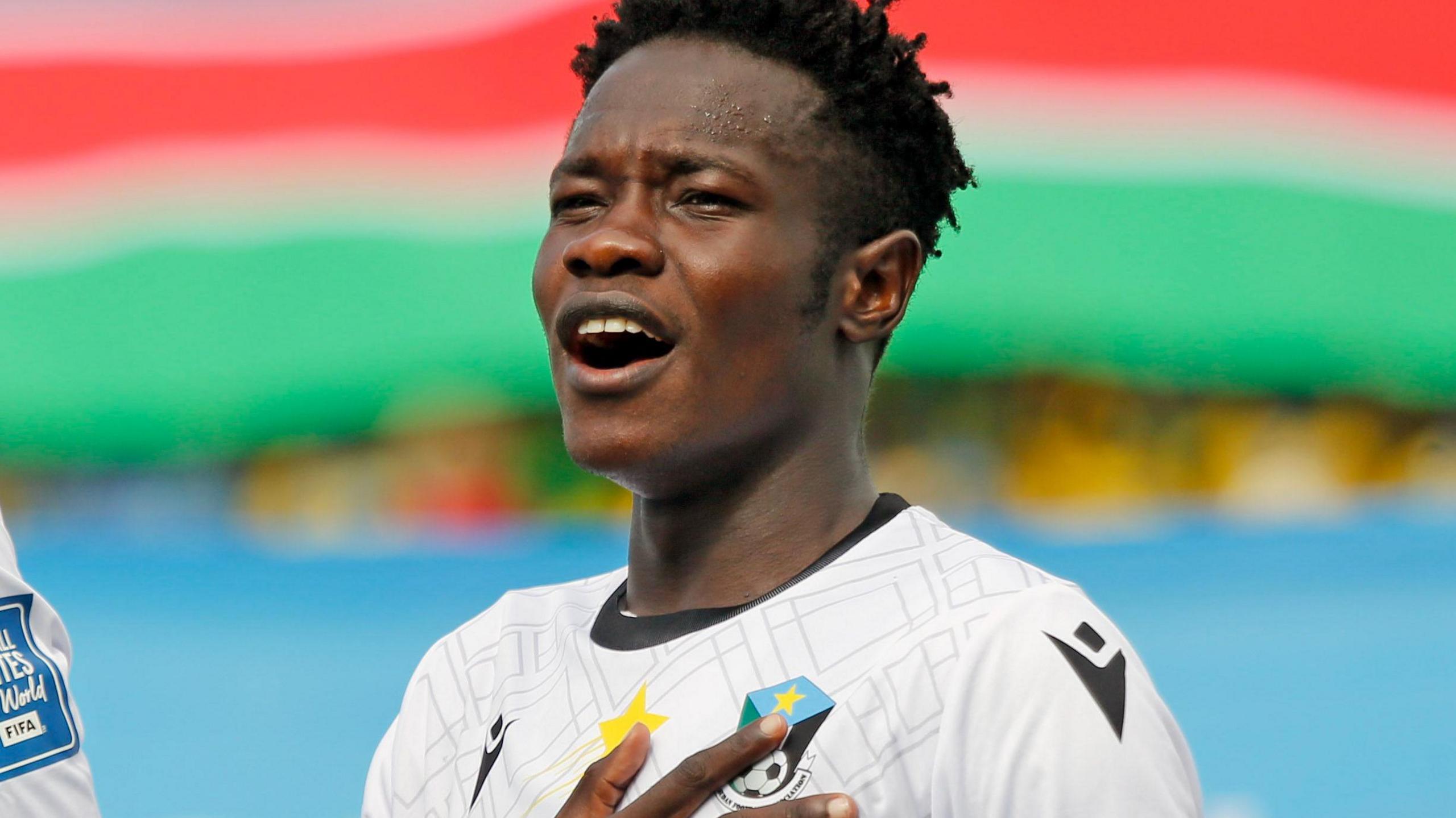 Paul Jawa of South Sudan puts his hand to his chest as he sings his country's national anthem