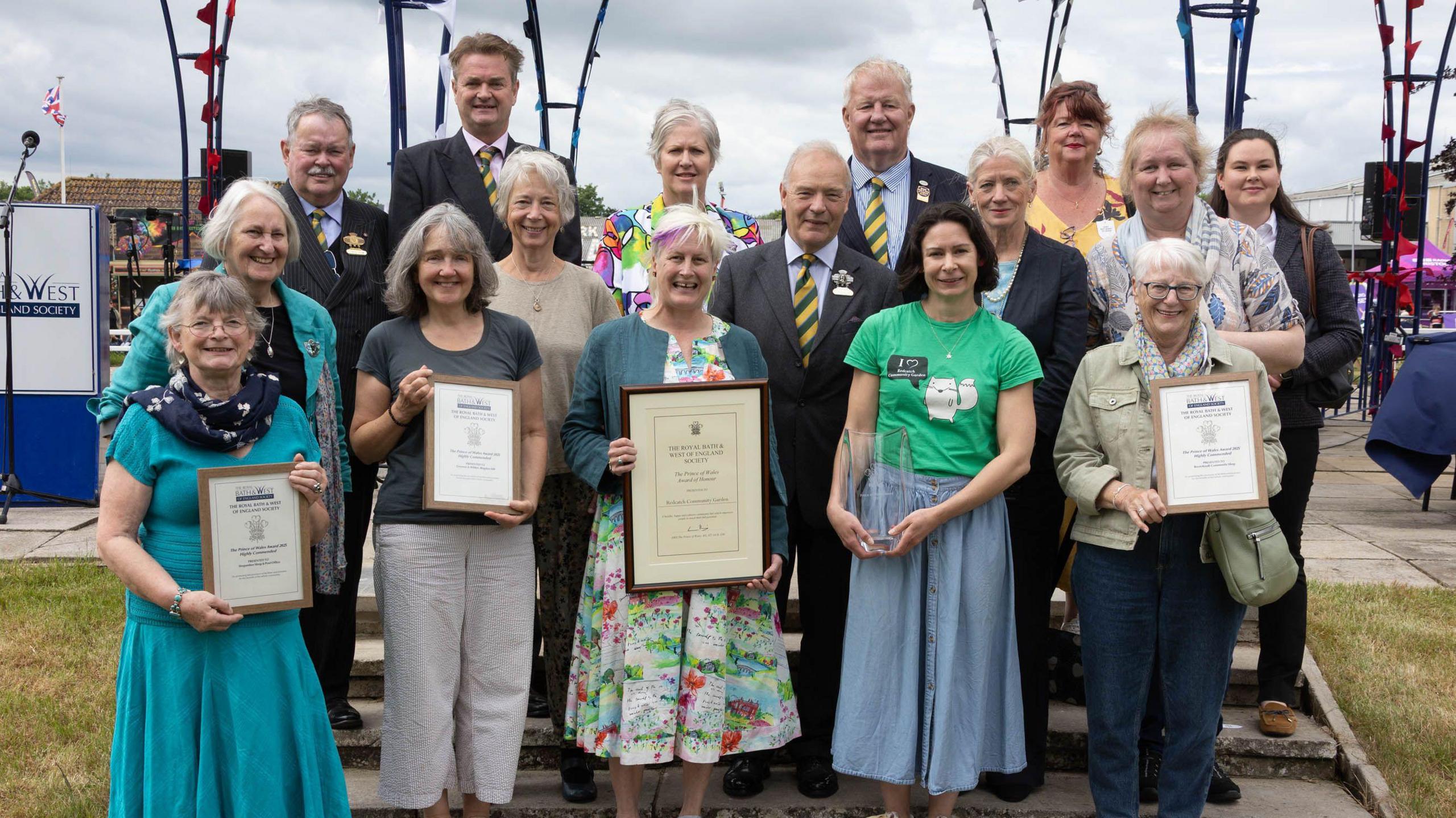 A group of men and women stand together with four women in the front row holding awards and certificates at the Bath and West Show.