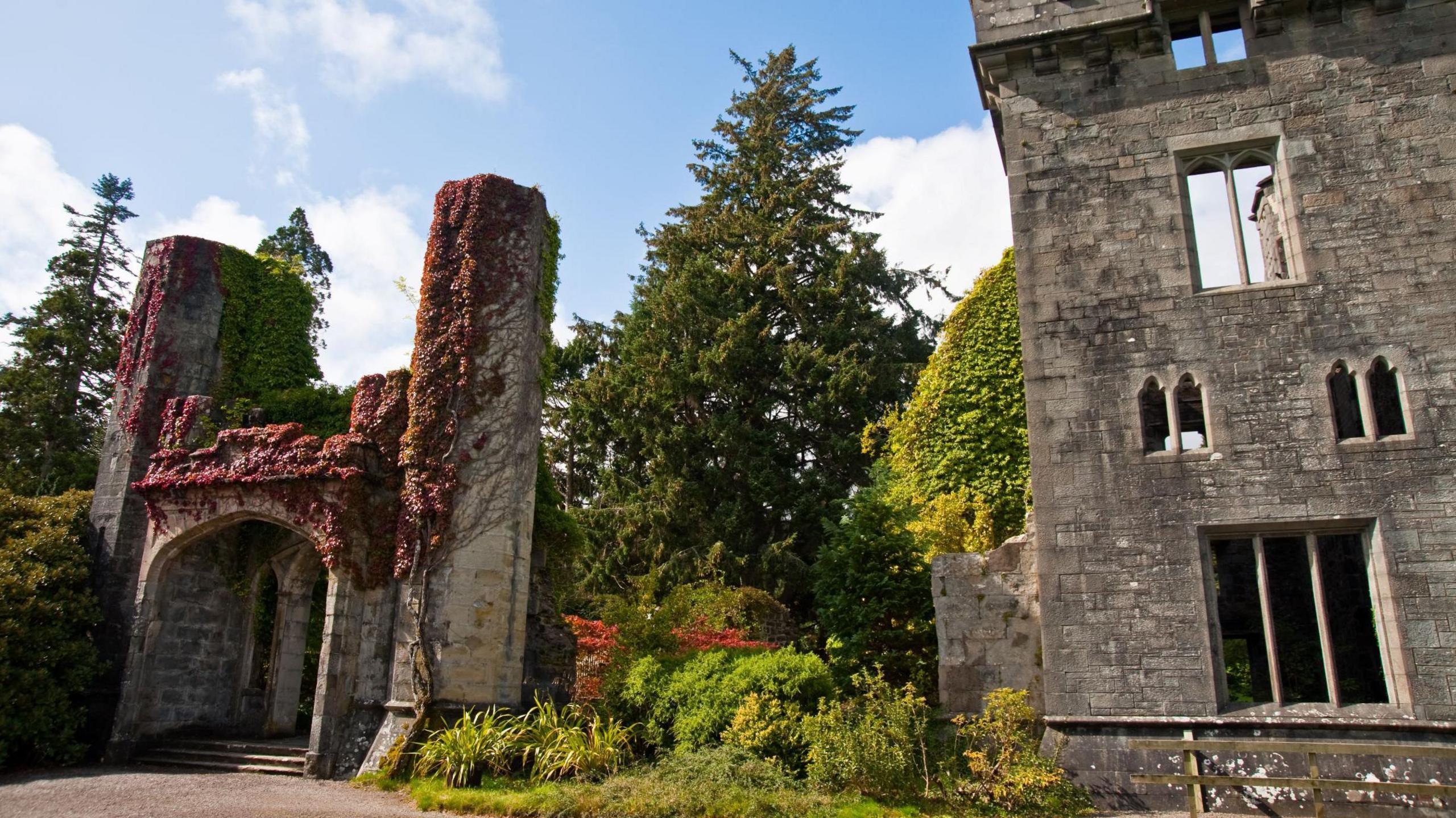 Skye's Armadale Castle is a ruin. There is an entrance with steps and a stone arch and large turreted property with narrow windows.