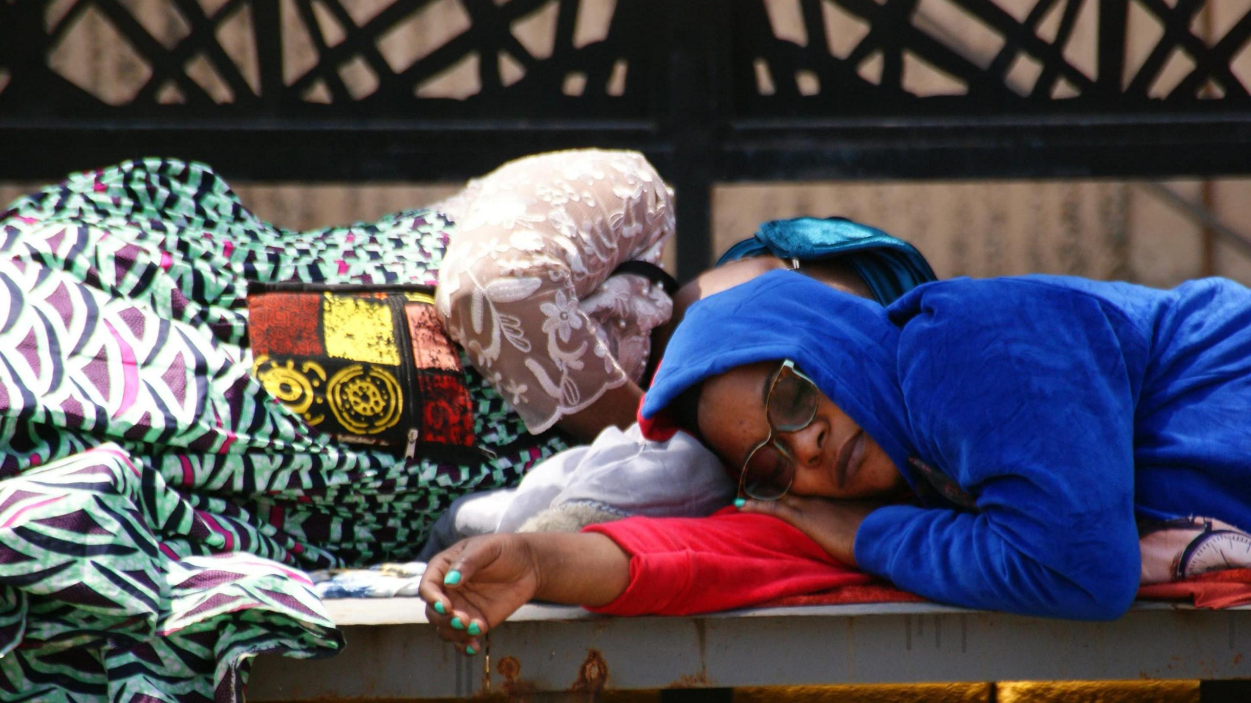 Two female passengers sleep at JKIA airport amid widespread disruption