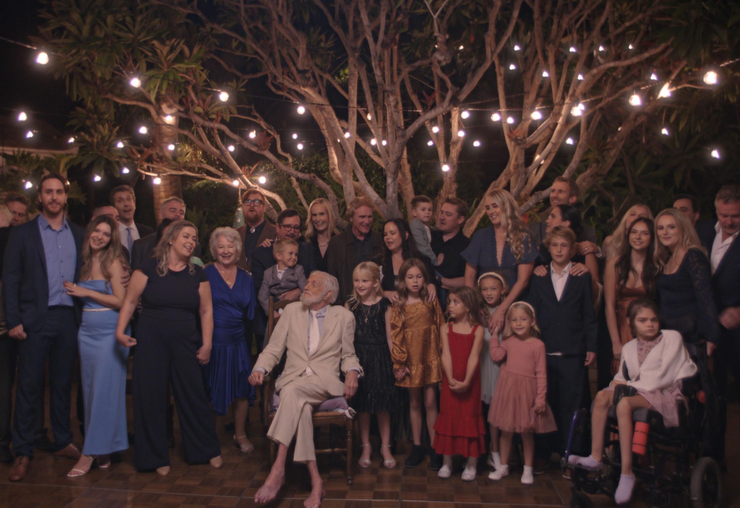 Actor Dick Van Dyke sits in a chair while surrounded by his children and grandchildren in Malibu