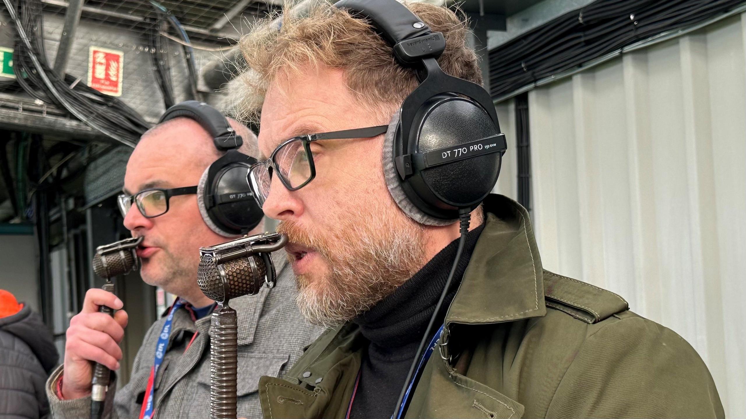 Cedric Anselin holding a microphone and broadcasting during a football match