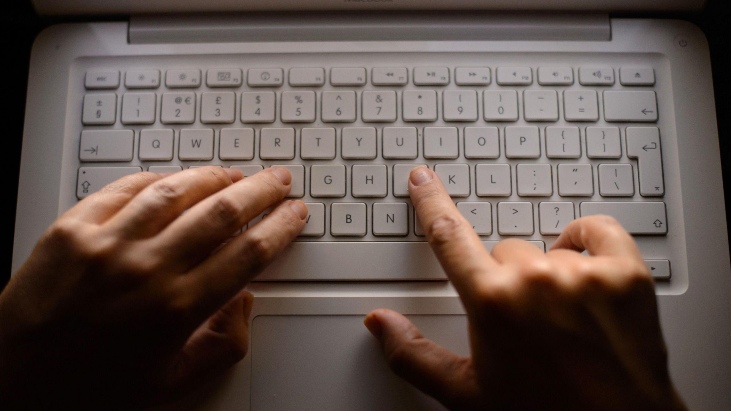 A person types on a laptop keyboard