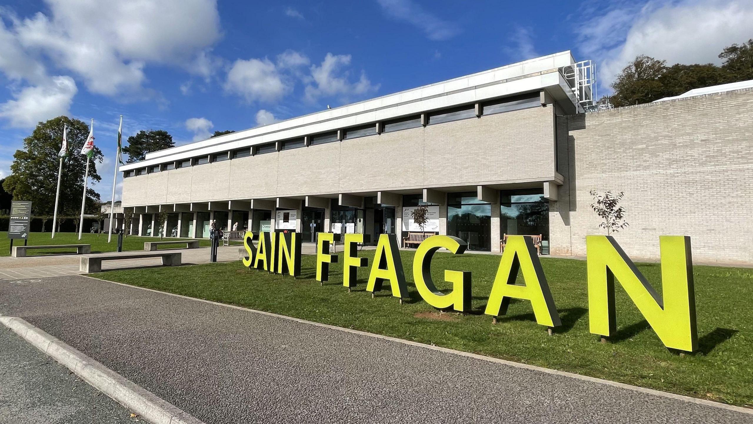 The exterior of museum with large yellow letters individually standing which spell out 'Sain FFAGAN'.