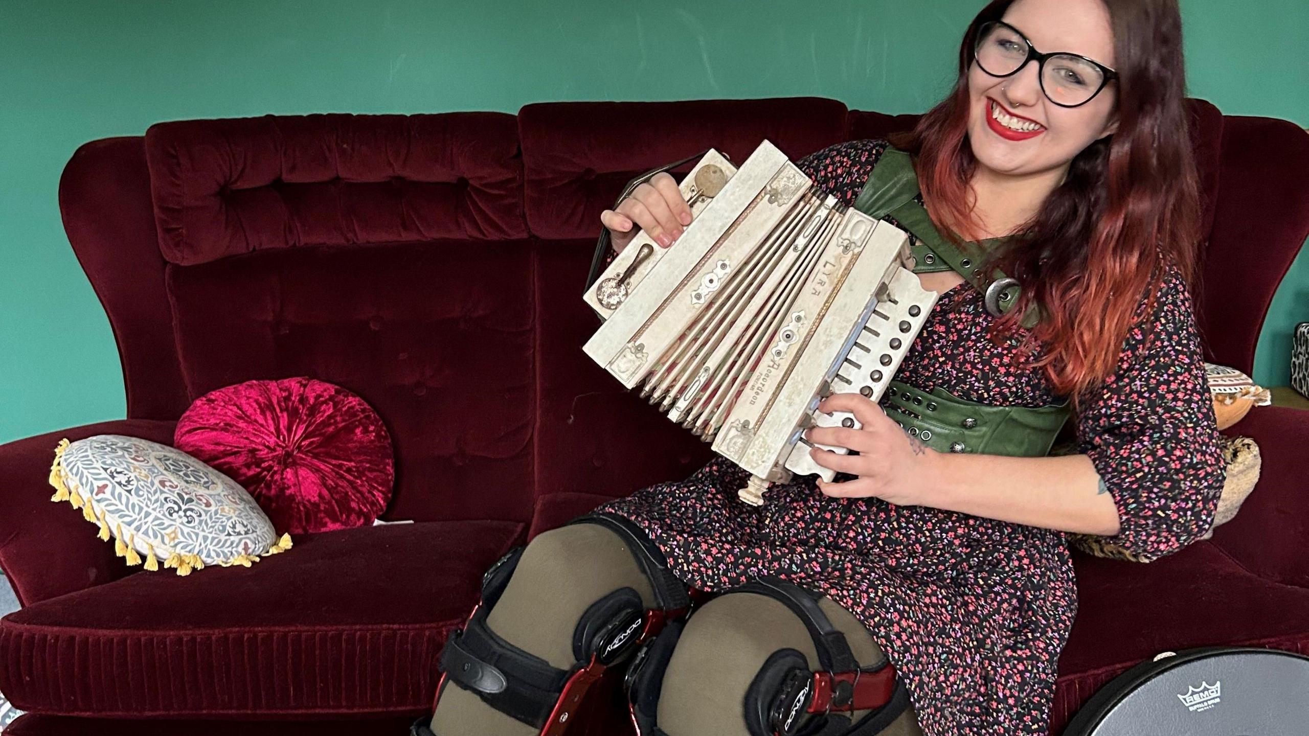 Ms Corr sits on the sofa wearing two, custom made leg braces to support her legs due to Ehlers Danlos Syndrome.