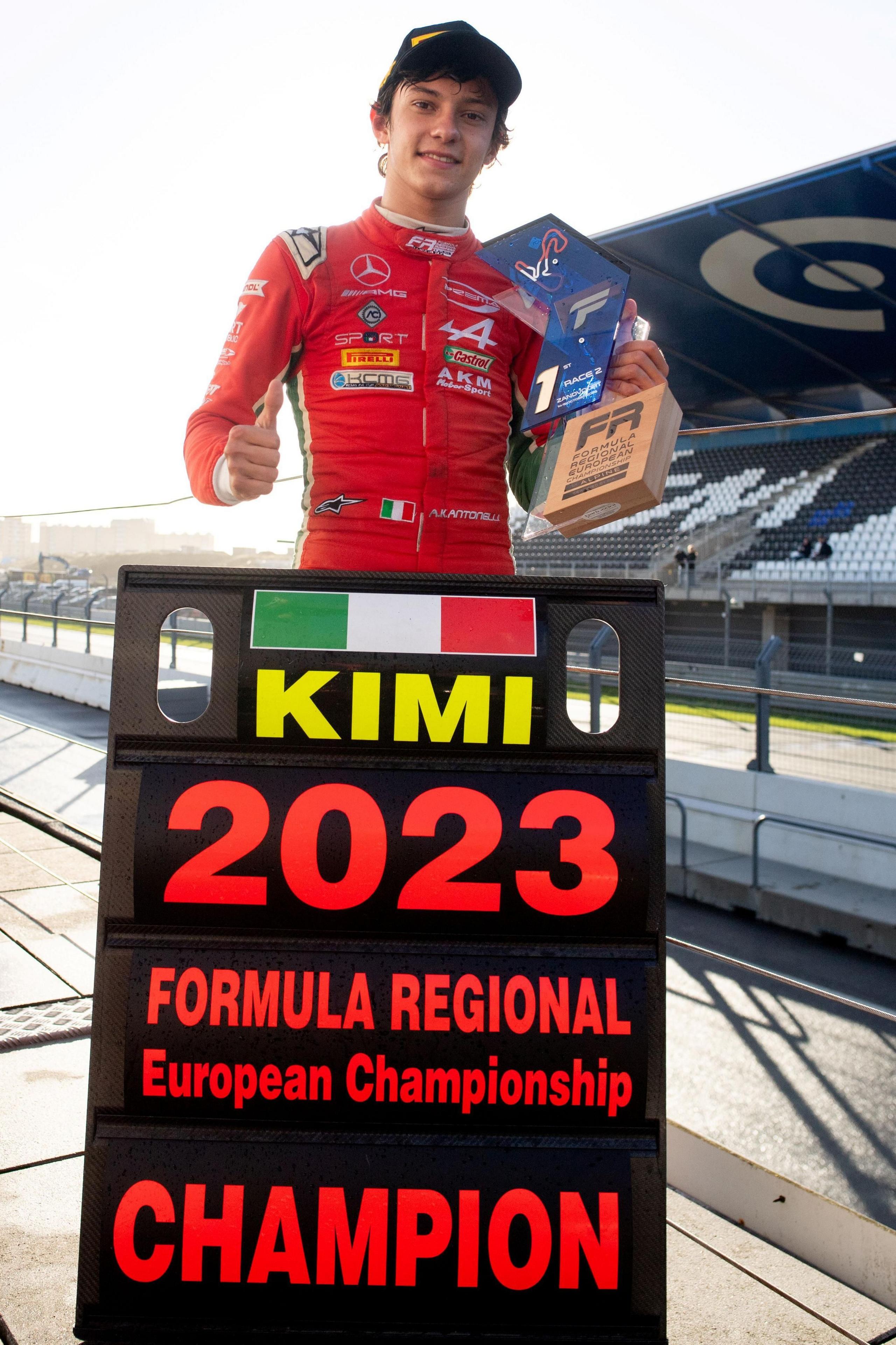 Kimi Antonelli standing behind a pit board sign that refers to him winning the 2023 Formula Regional European Championship