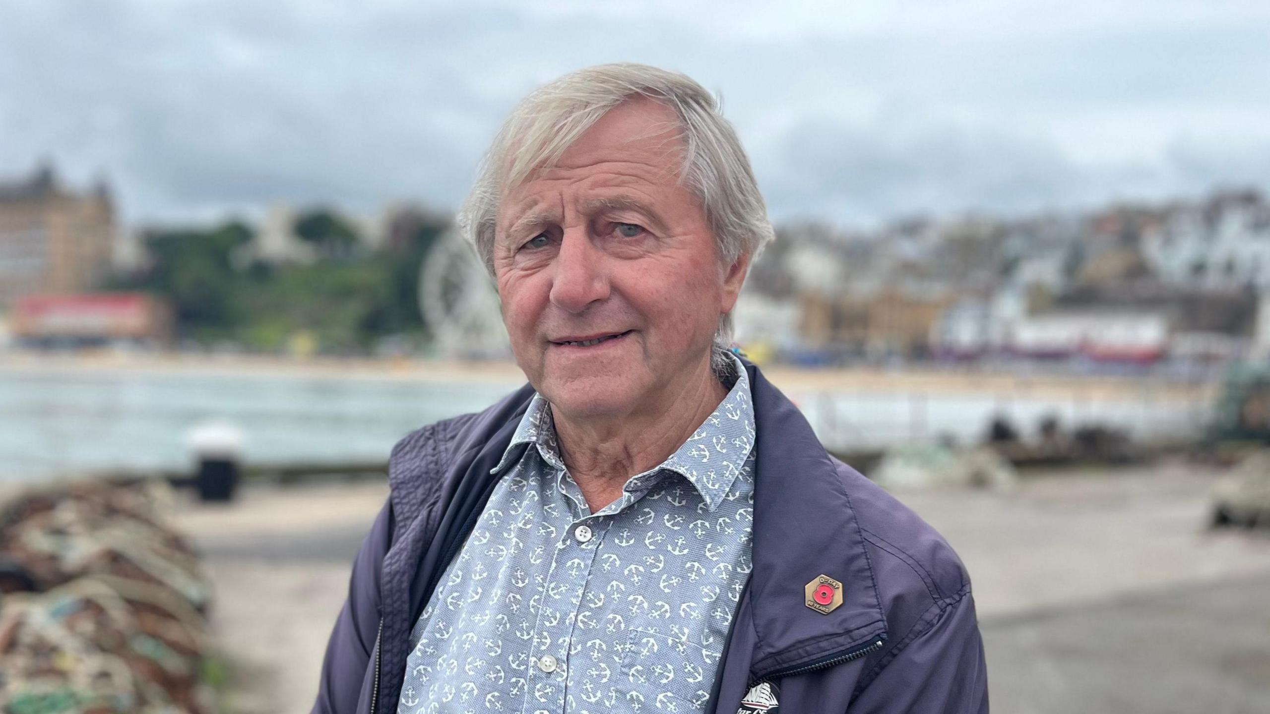 Man wearing a shirt stood on the harbour looking at the camera