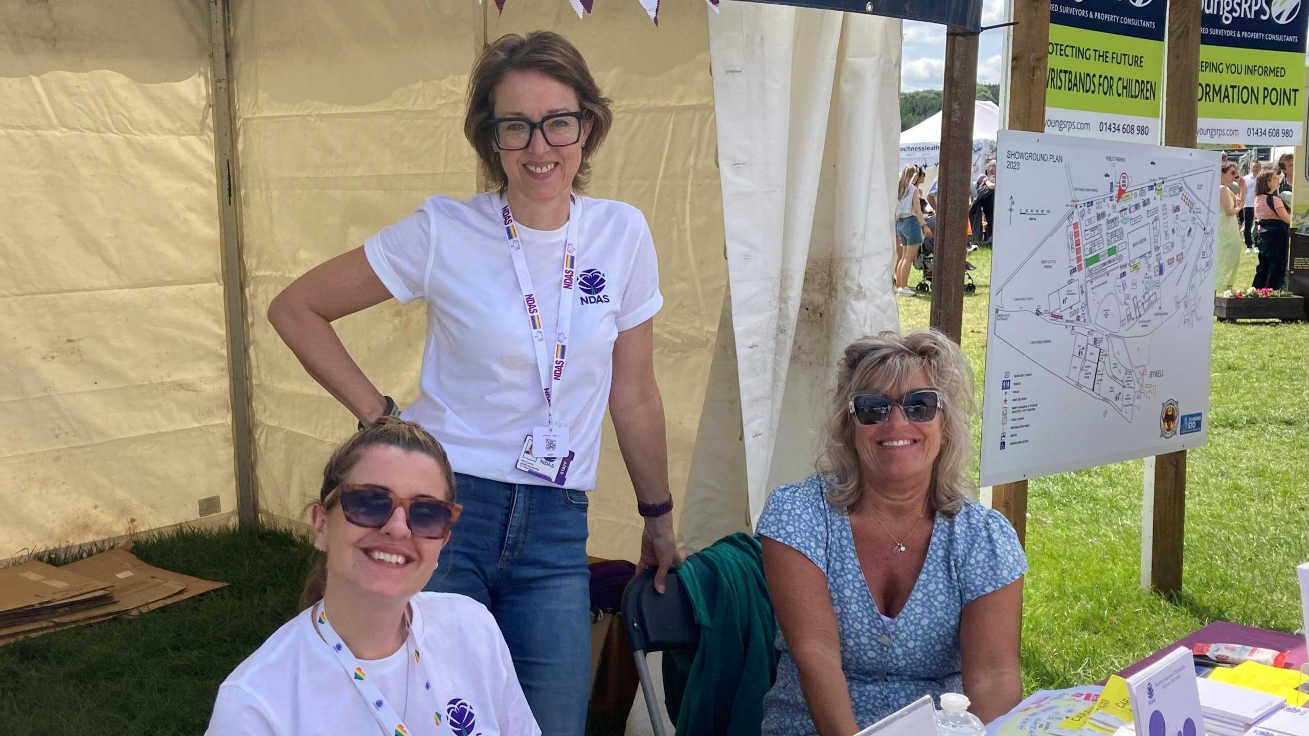 Three smiling women in a tent at the show 