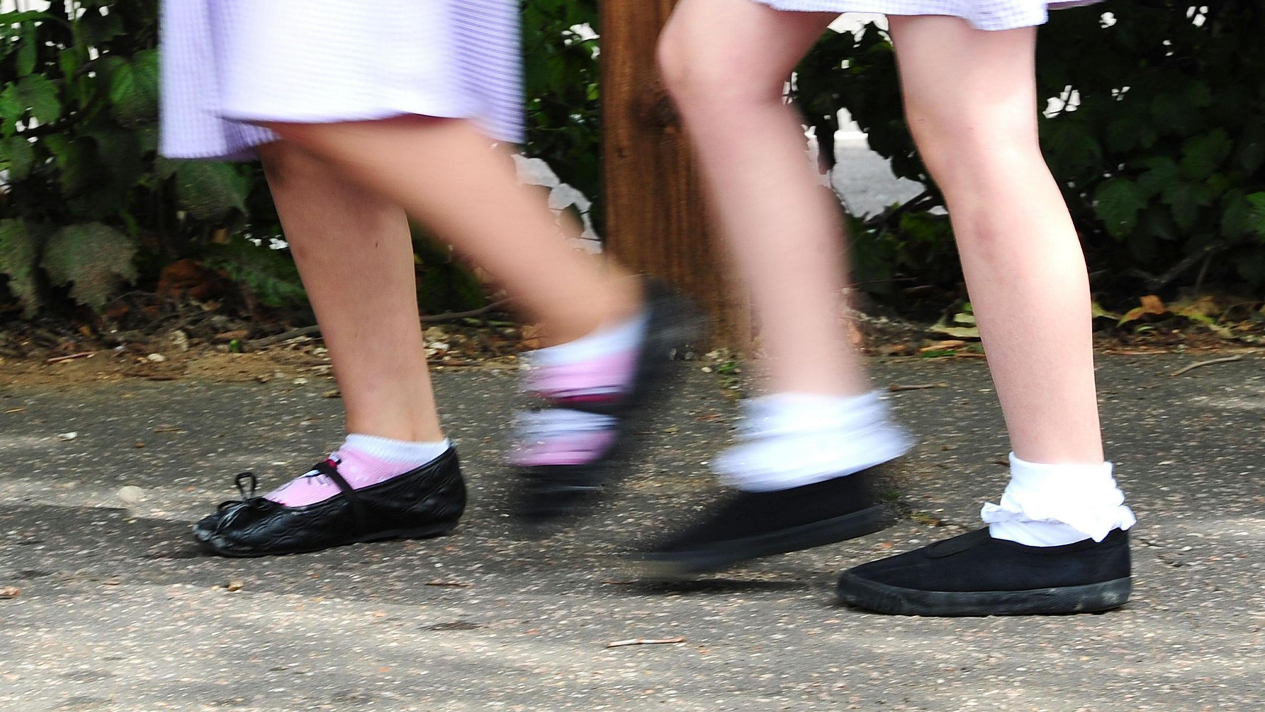 A picture showing the legs of two primary-school age girls in their uniforms