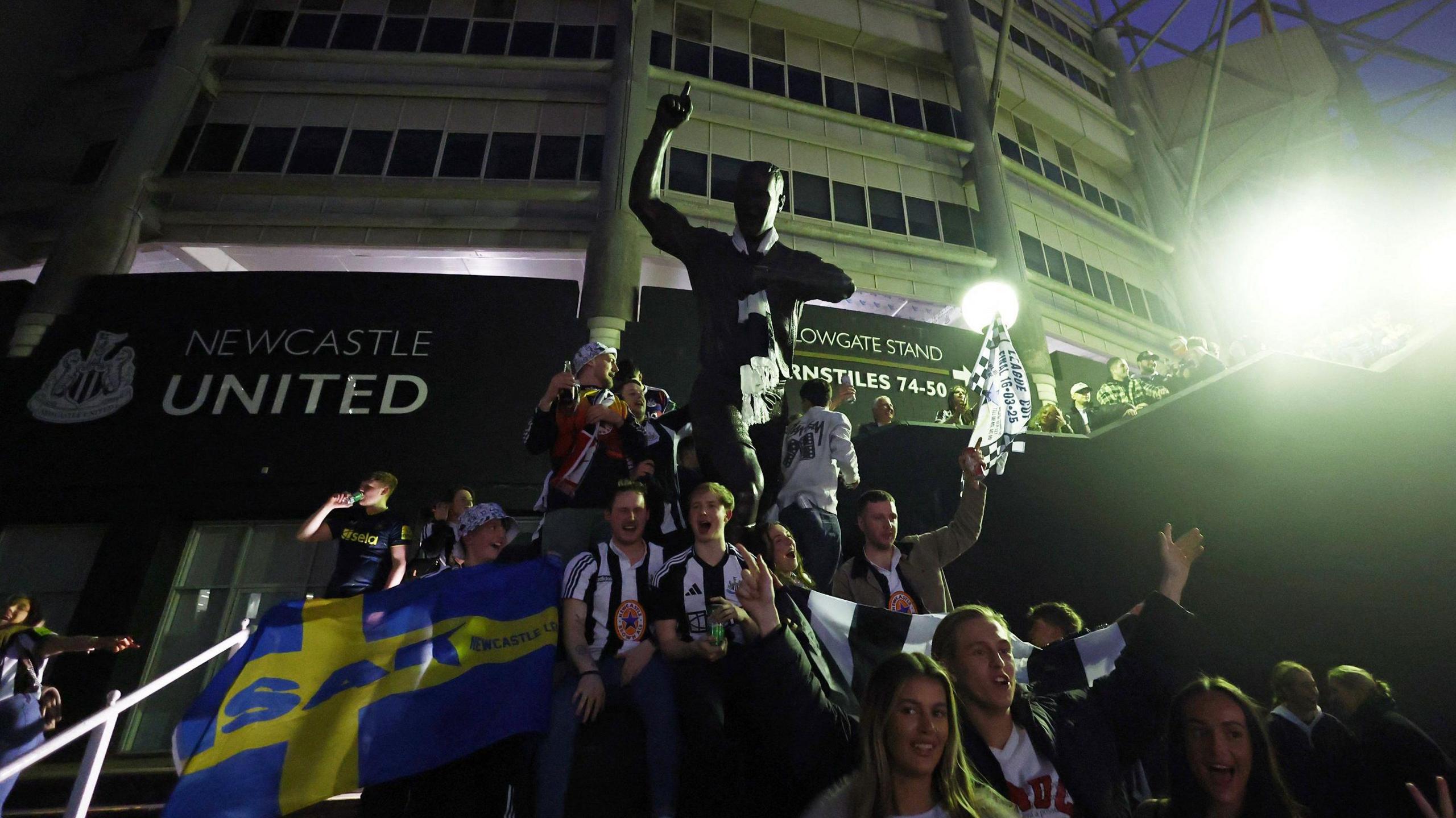 Newcastle fans celebrate around Shearer's statue at St James' Park on Sunday evening