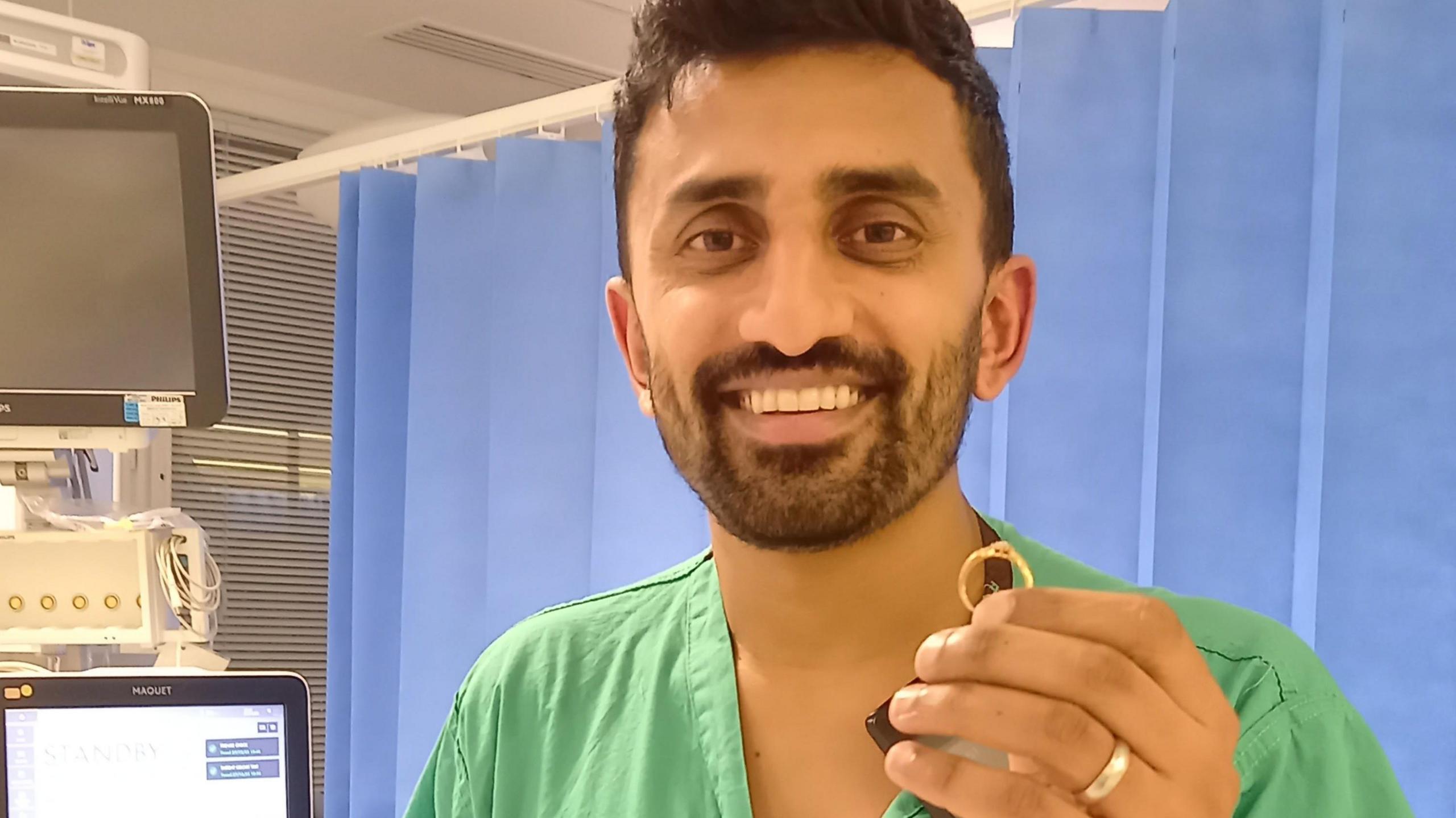 Suraj Shah wearing hospital scrubs and holding the ring