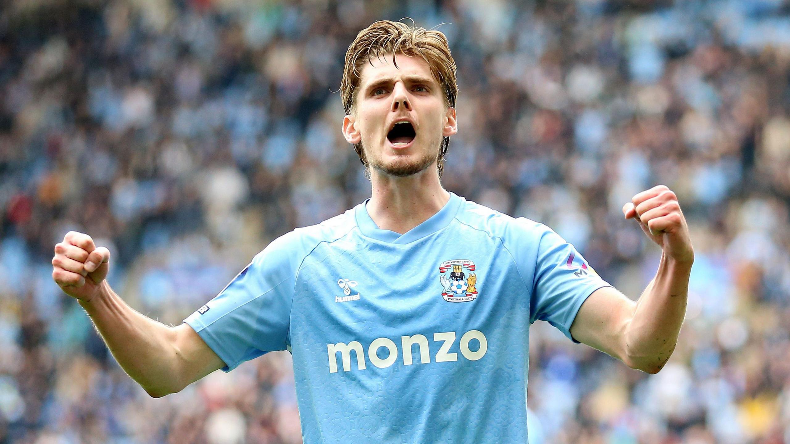 Jack Rudoni, in his Sky Blue Coventry City shirt, double fist pumps the air in celebration at scoring