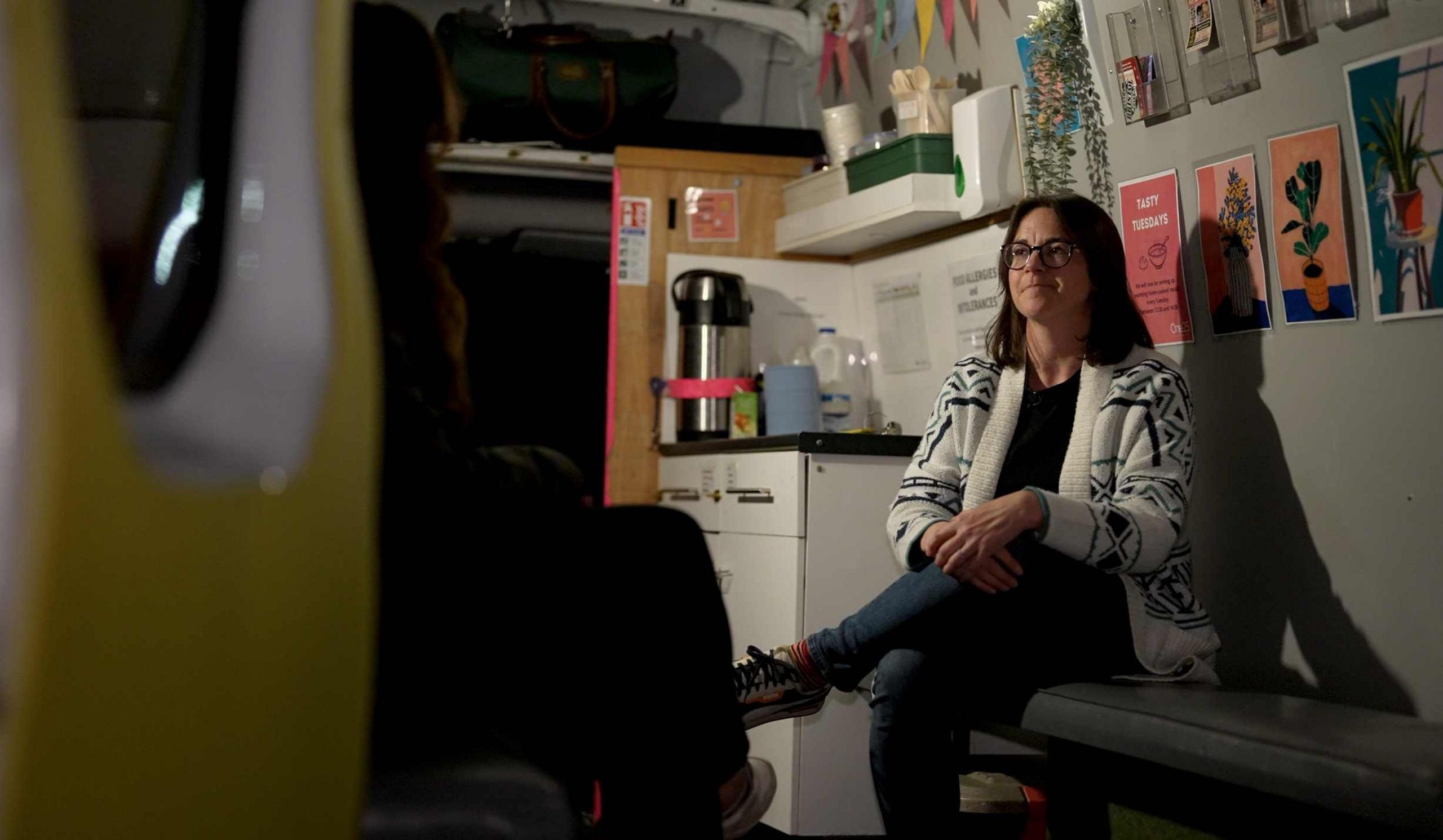 Rachel White sits inside the van talking to the reporter whose back is to the camera