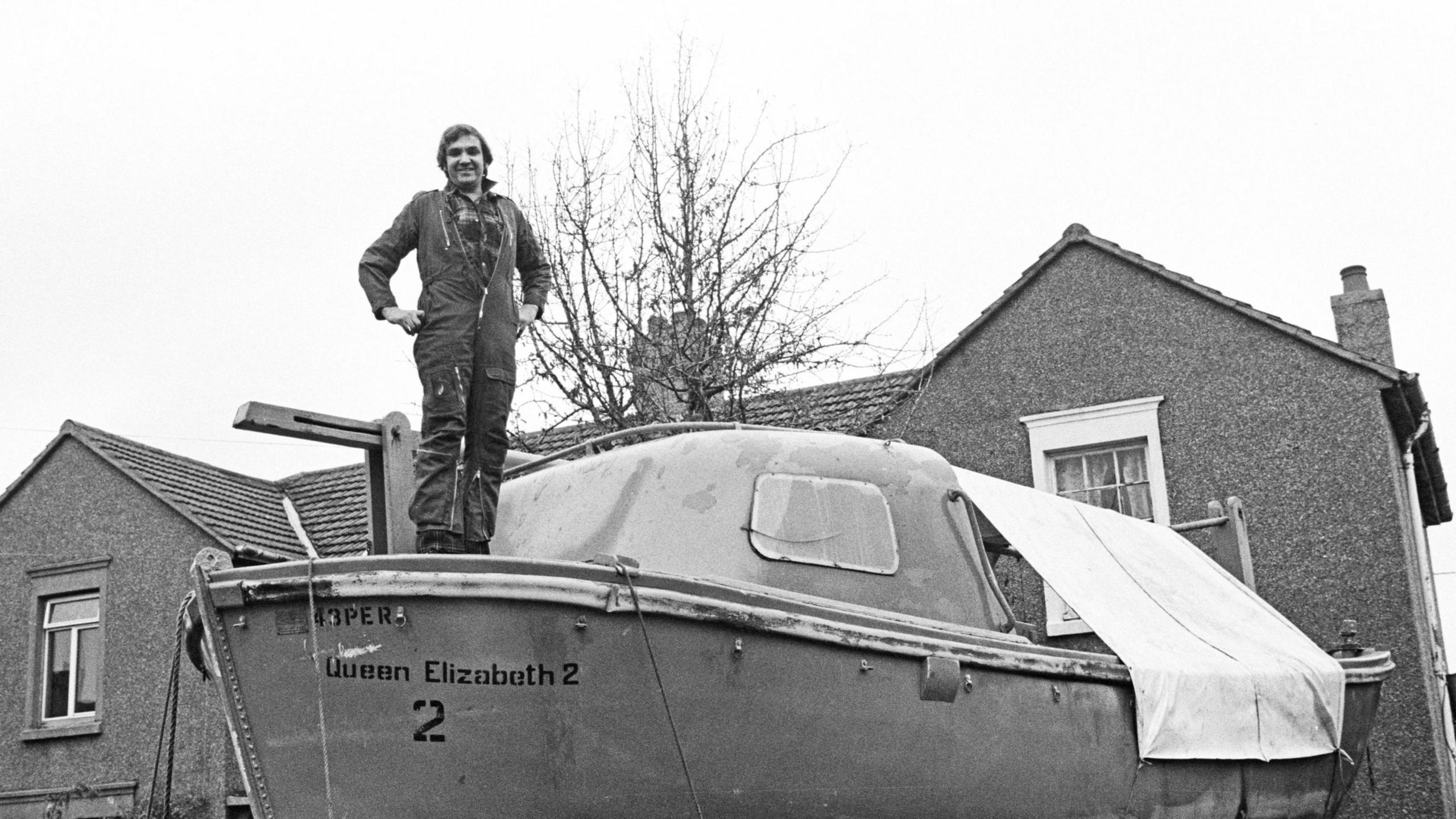 David Lawrence standing on a QE2 lifeboat outside his home