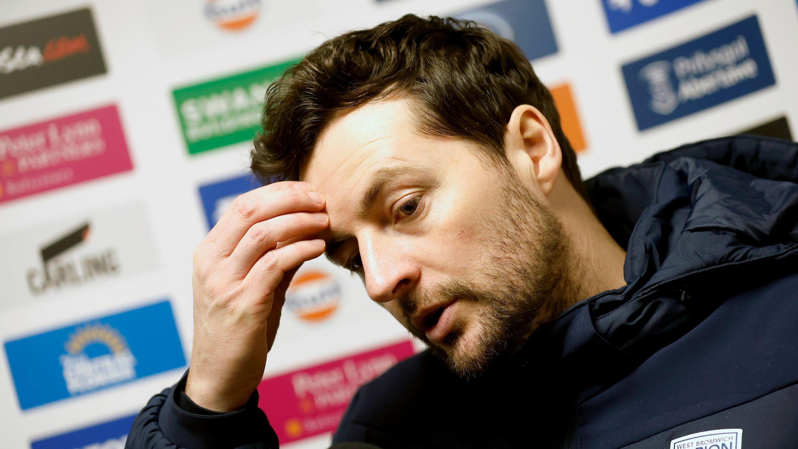 Ryan Mason with his hand on his head speaking to the media