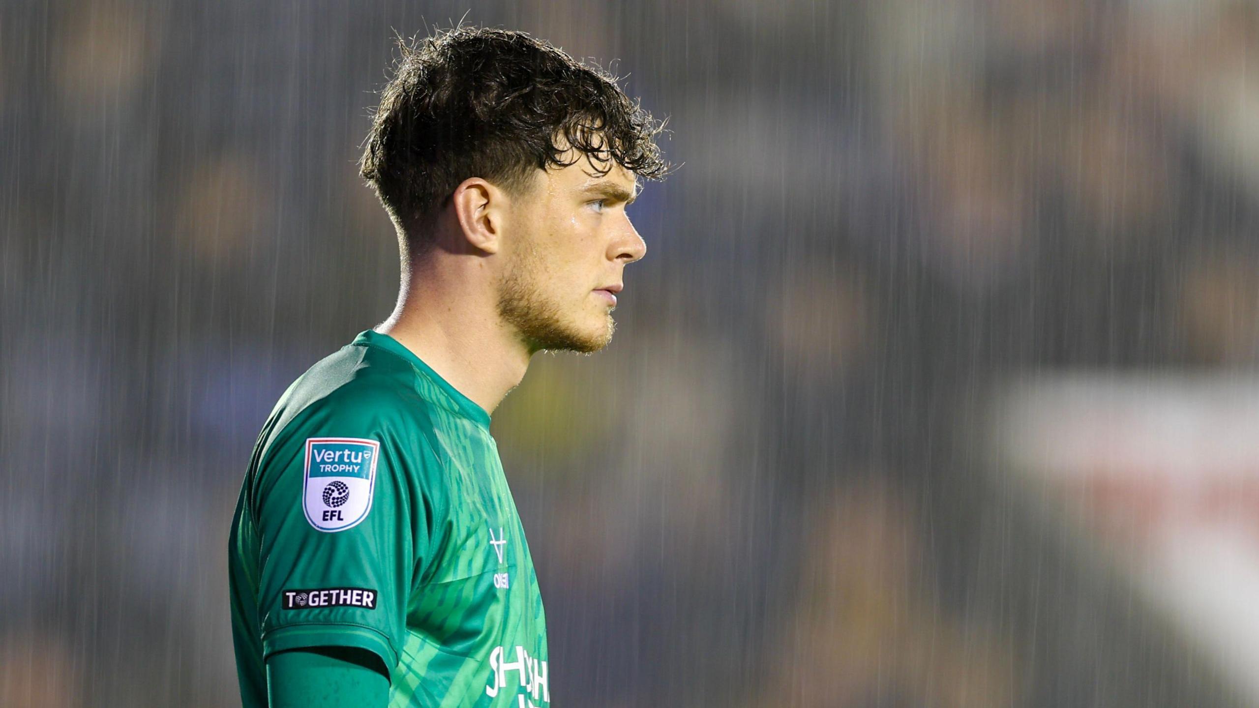 Shrewsbury Town goalkeeper Will Brook stands watching on in rain during a match
