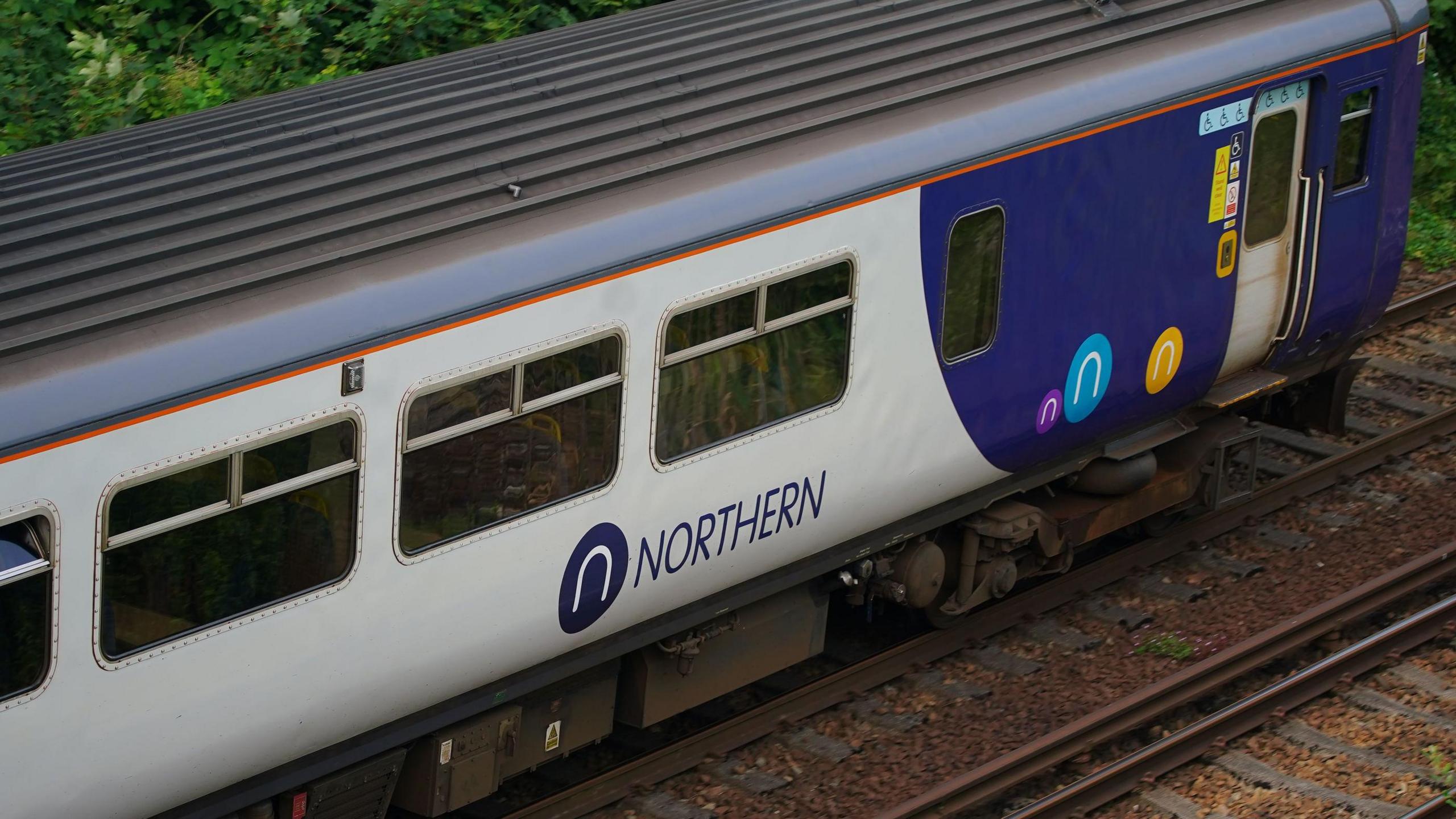 A Northern railway train with the grey and purple livery at Hunt's Cross station, Liverpool