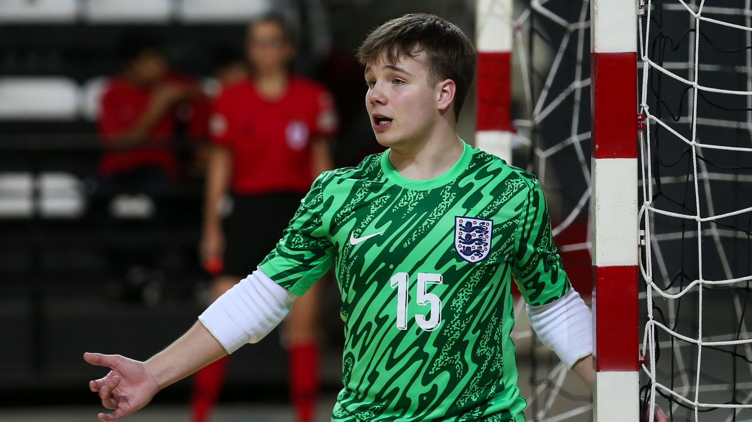 Ben Taylor, a teenager with brown hair, playing futsal in a green England shirt