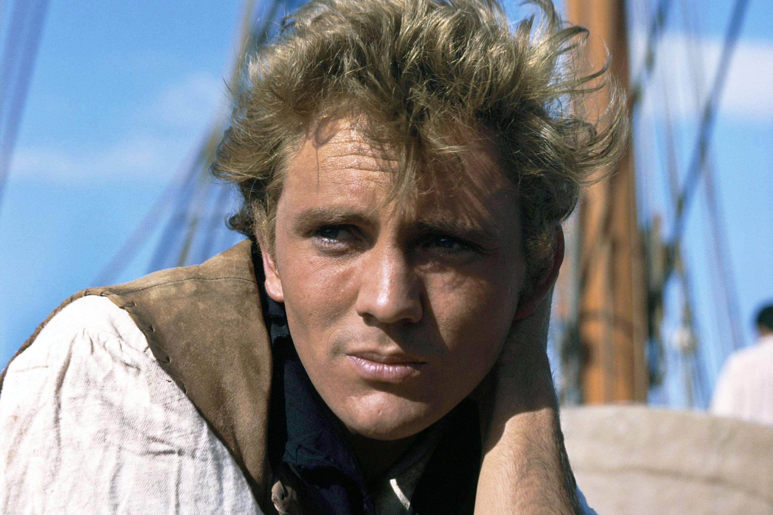 Një Terence Stamp i ri i fotografuar në sheshxhirimin e filmit të tij të vitit 1962, Billy Budd. Ai është mbështetur në njërin krah në bordin e një anijeje me vela, i veshur me një këmishë të gjerë, të bardhë të çelët dhe një jelek ngjyrë kafe. Sfondi tregon pjesë të anijes, duke përfshirë direkë të gjatë prej druri dhe litarë për litarë, në sfondin e një qielli të kaltër të kthjellët. Skena sugjeron një mjedis detar, ndoshta gjatë ditës me mot të qetë.