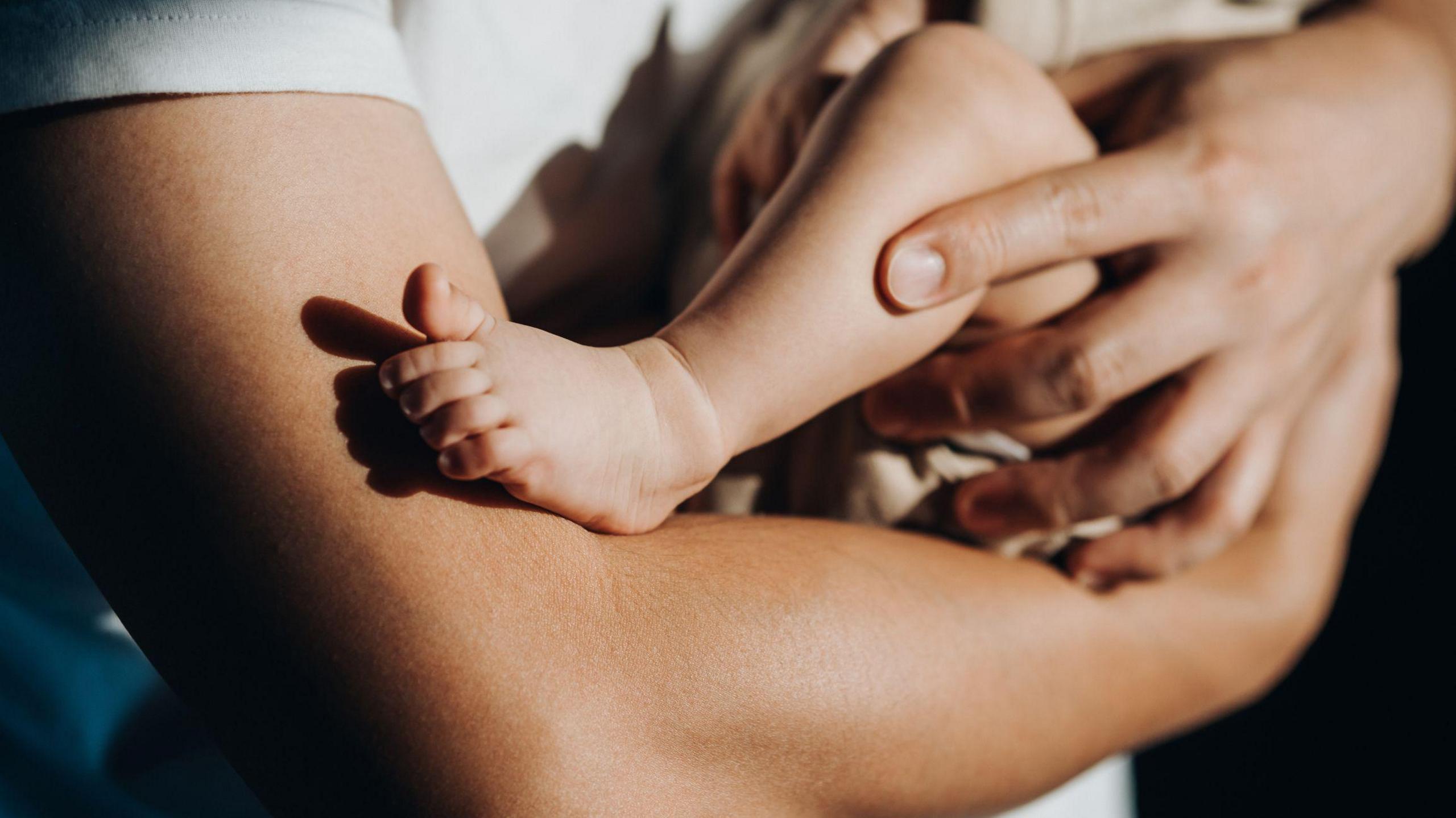 A close up of a person's arms holding a small baby 