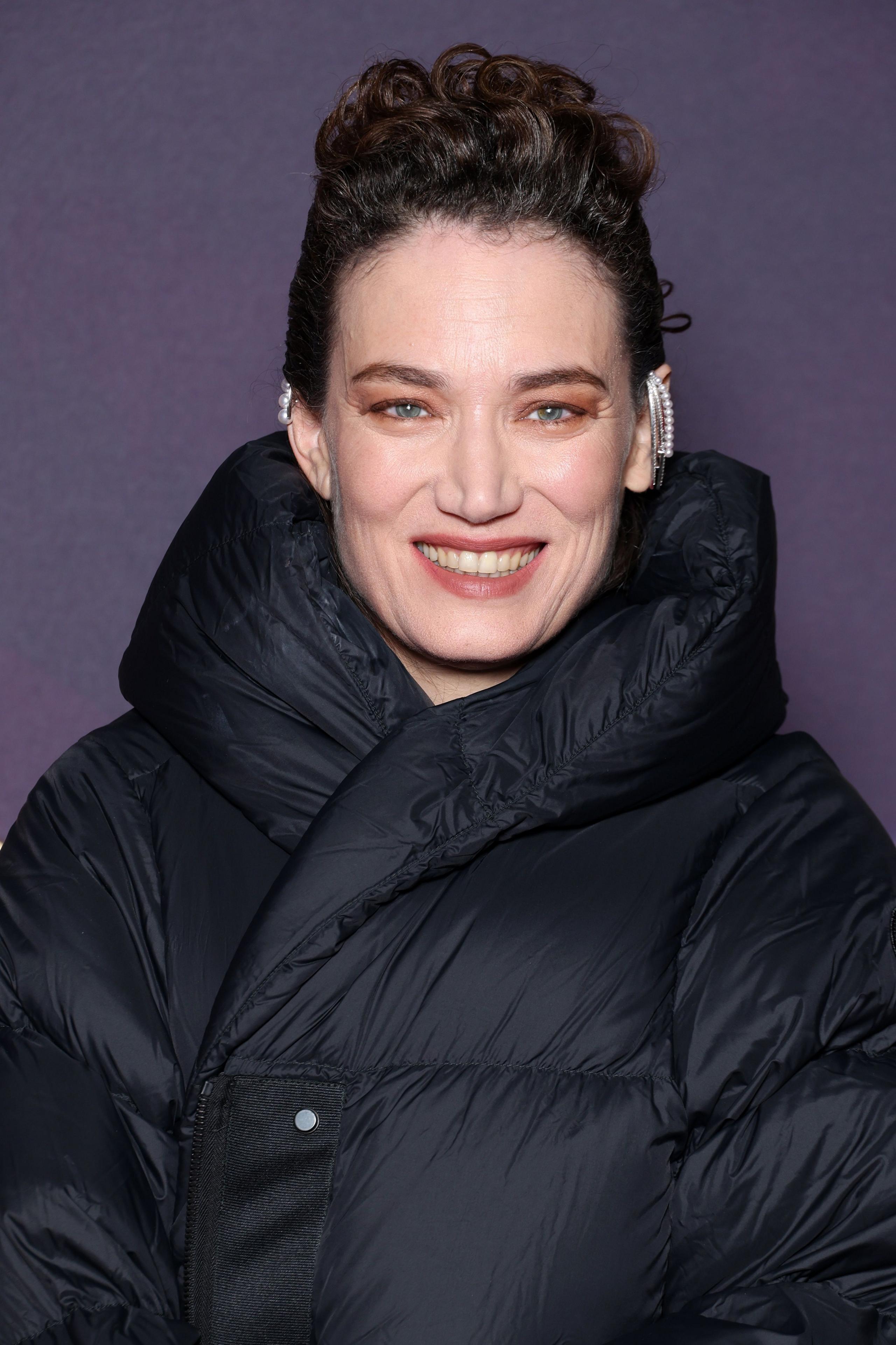 Coralie Fargeat in a black puffa coat over her long, black outfit