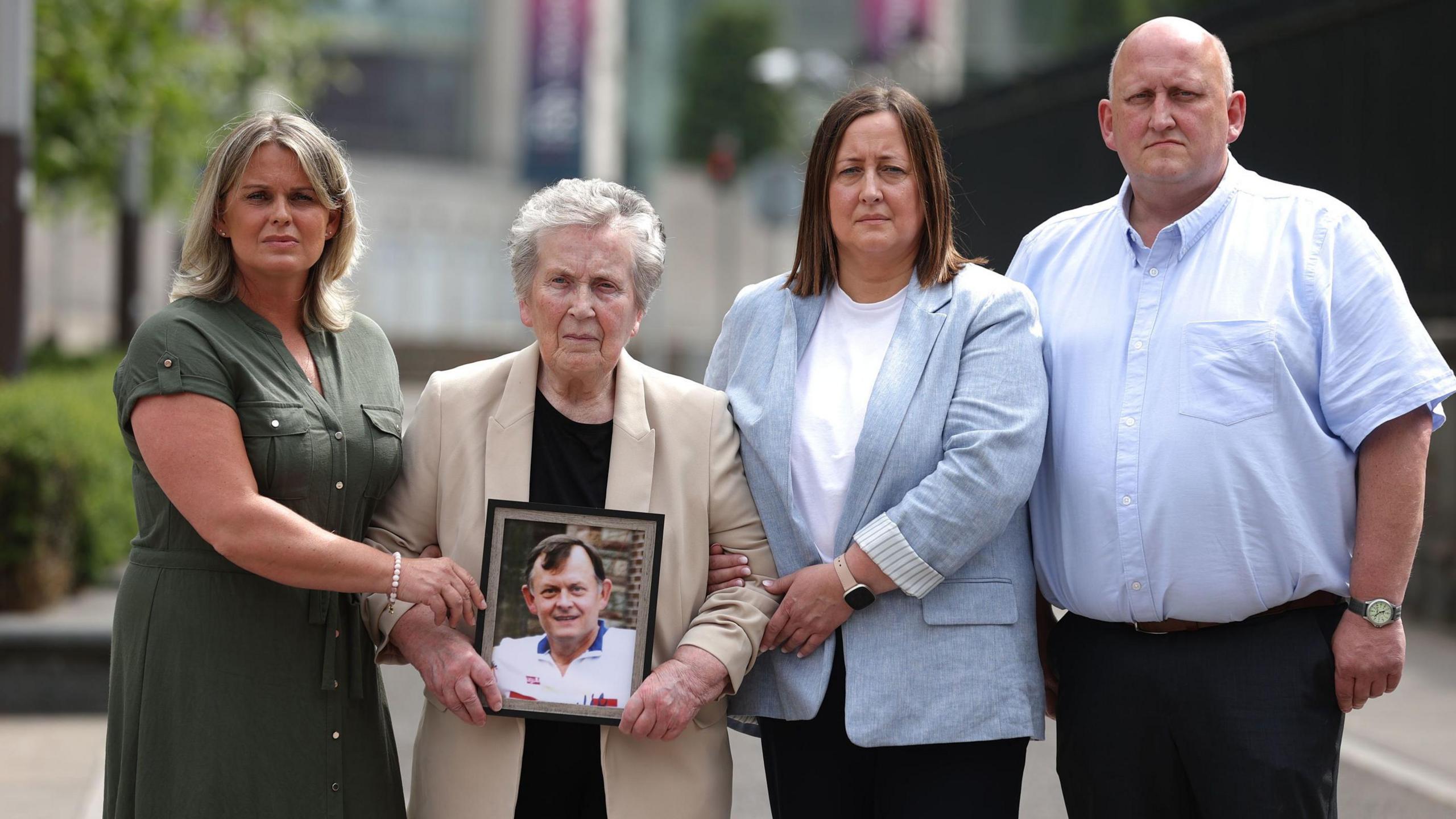 Group of Sean Brown's family holding a framed photo of Sean Brown outside court 
