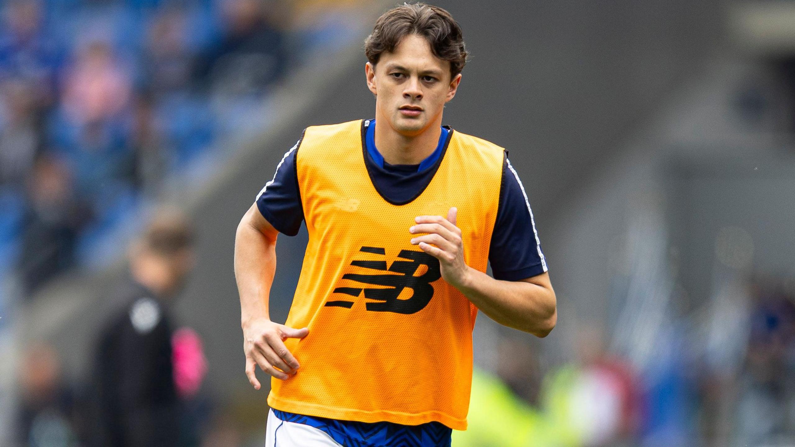 Perry Ng warming up for Cardiff City wearing training kit and an orange bib