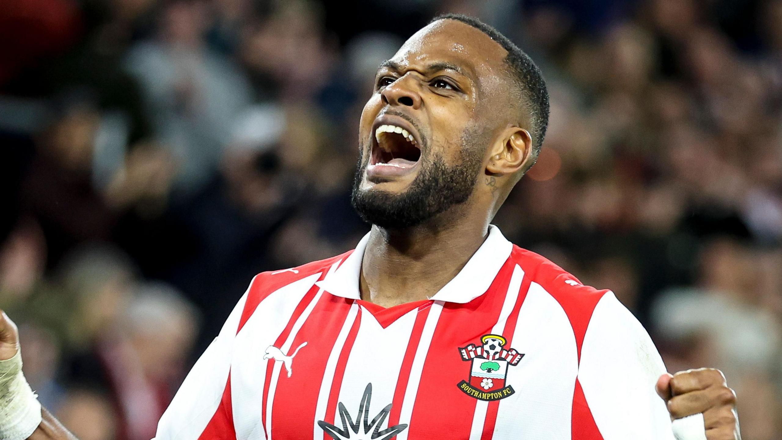 Cyle Larin, wearing Southampton's red and white home shirt, celebrates a goal